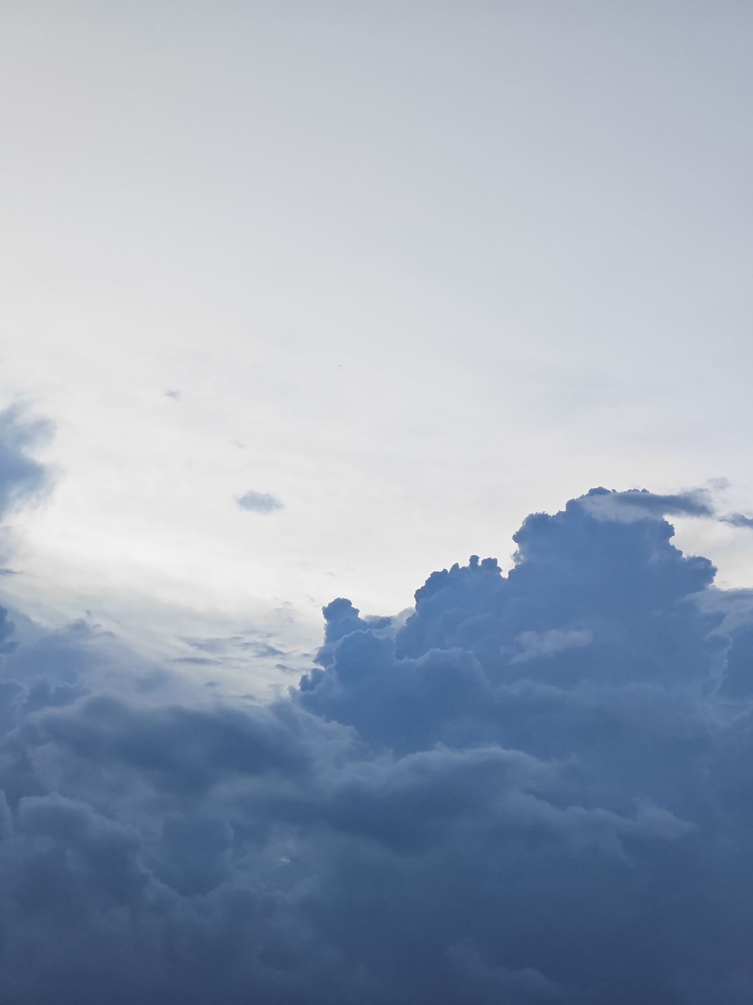 The image depicts a dynamic sky filled with dark, heavy clouds, likely indicating an approaching storm or recent rainfall. The clouds are a deep blue-gray, with some lighter, wispy formations scattered higher up. The lighting suggests it is either early morning or late afternoon, with the sun diffused by the cloud cover. There are no people, subjects, or objects visible in the frame, nor any identifiable landmarks that would place it specifically within Đà Nẵng, Vietnam. The scene is entirely composed of atmospheric elements.