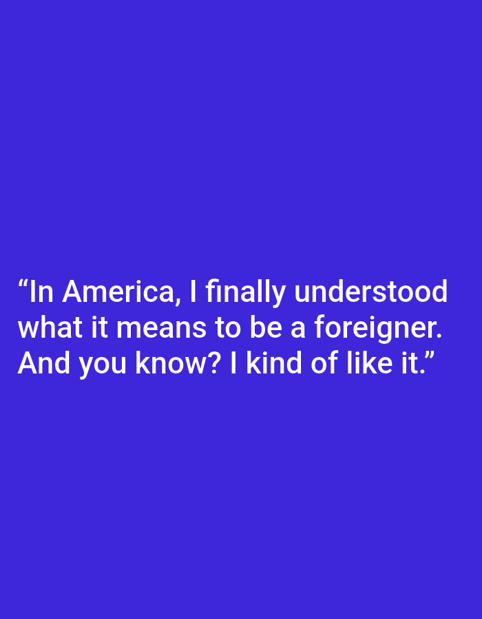 This is a digitally generated image with a solid, deep blue background. White text is overlaid on the bottom half of the image, presenting a quote. The text reads: "In America, I finally understood what it means to be a foreigner. And you know? I kind of like it." There are no visible subjects, objects, or scenery. The image appears to be a graphic design meant to convey a message or thought.