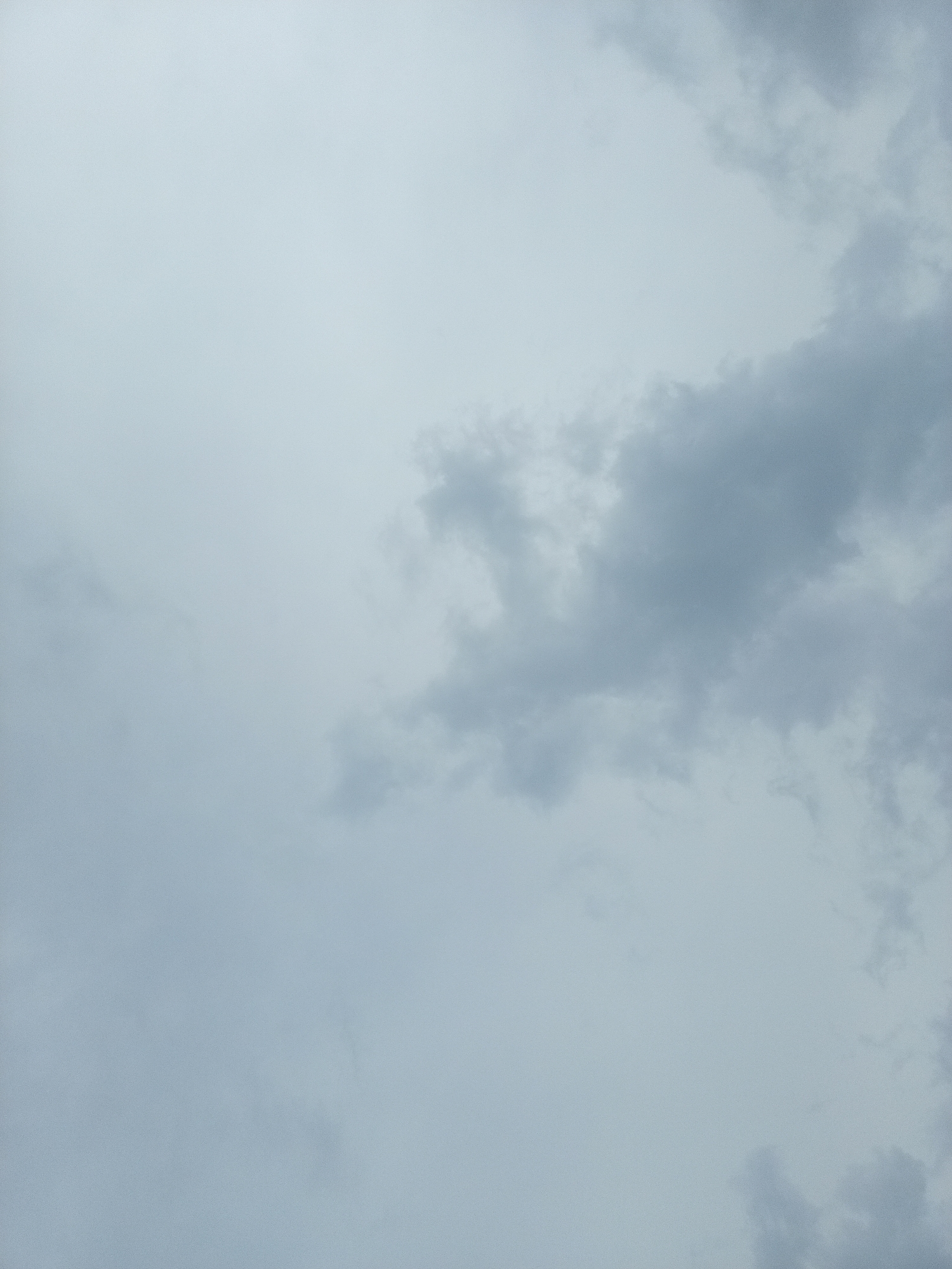 A photograph captures a cloudy sky above New Stadium, Nigeria. The clouds are a muted gray, obscuring much of the sky and suggesting overcast weather. There are no people, subjects, or objects visible in the frame, only the atmospheric conditions of the sky. The environment depicted is solely the sky itself, with the gray clouds taking up the entire image.