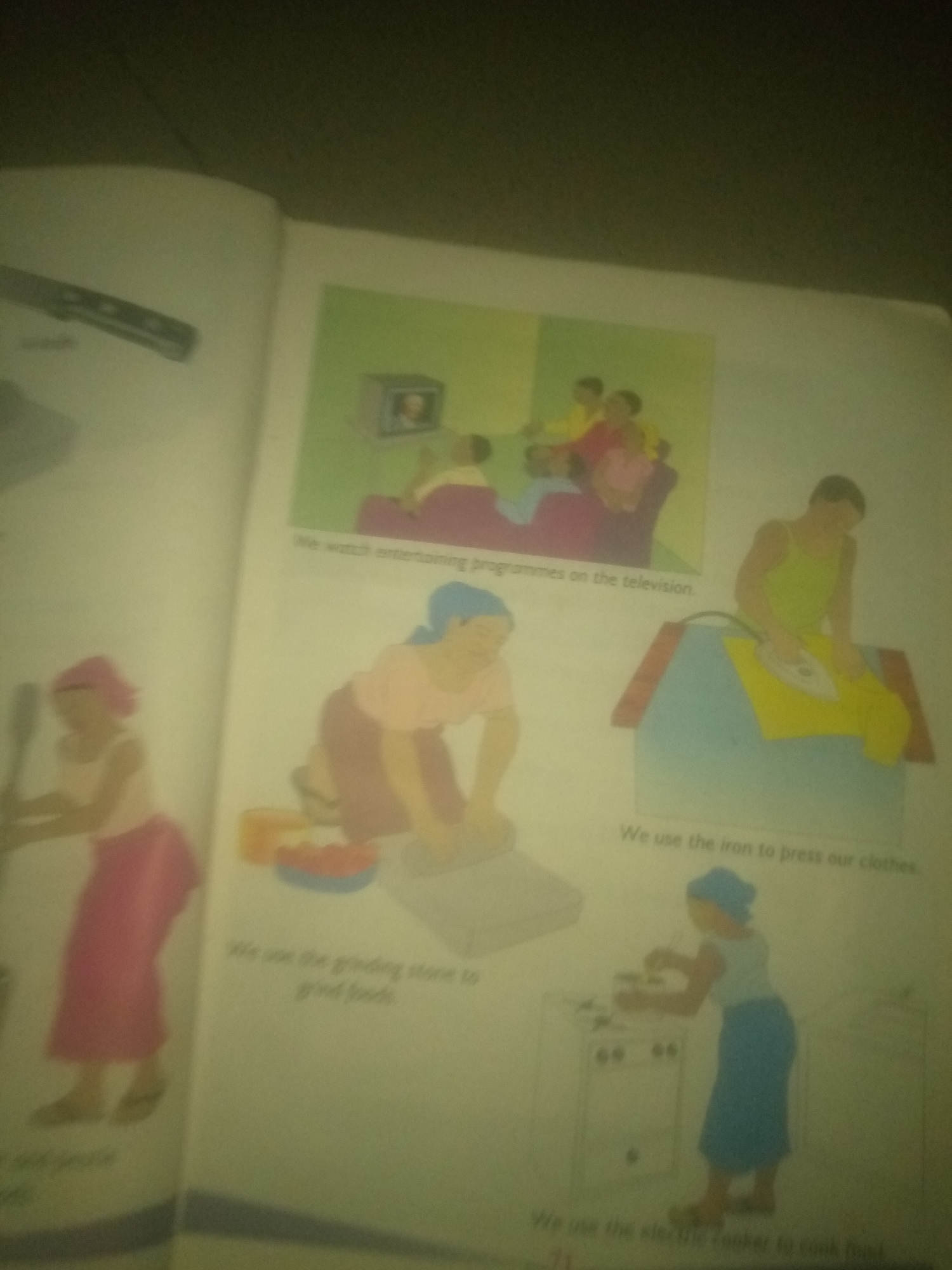 The image displays a page from a book, likely an educational one, featuring several illustrations depicting everyday activities and objects. The content is presented in English, with captions accompanying each illustration. The scene is set indoors, and the lighting appears to be dim, casting a slight yellow hue over the image. There are no visible elements that suggest a specific location within the city of Jalingo, Nigeria.
The illustrations include:
1. A family sitting and watching television, with a caption that reads, "We watch entertaining programmes on the television."
2. A woman using a grinding stone to process food, with a caption stating, "We use the grinding stone to grind foods."
3. A person ironing clothes with an electric iron, accompanied by the caption, "We use the iron to press our clothes."
4. A person standing in front of an electric cooker, presumably cooking, with the caption, "We use the electric cooker to cook food."
5. Another illustration shows a person, possibly a woman, holding a kitchen utensil, potentially cooking or preparing food, with an illegible caption.
6. There is also a partial view of what appears to be a knife on a surface in the upper left corner of the page.
The overall impression is a collection of didactic illustrations showcasing common household activities and appliances, likely intended for children.