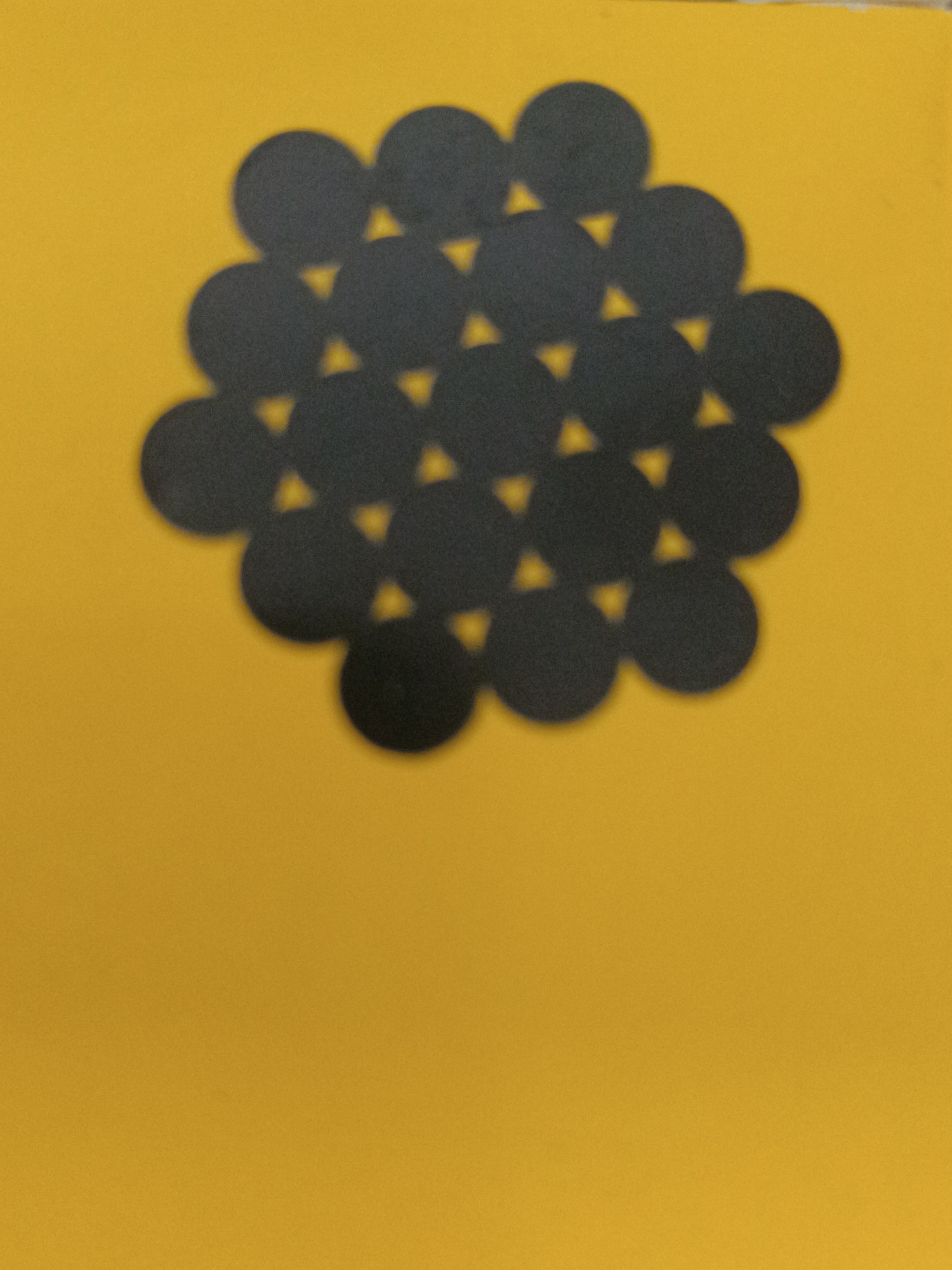 The image displays a pattern of black circles arranged in a hexagonal close-packed structure on a yellow background. There is no discernible connection to Taraz city administration, Kazakhstan, as the image appears to be a flat lay or abstract composition of circles. There are no people, actions, or interactions depicted. The environment is limited to the yellow background and the black circles.