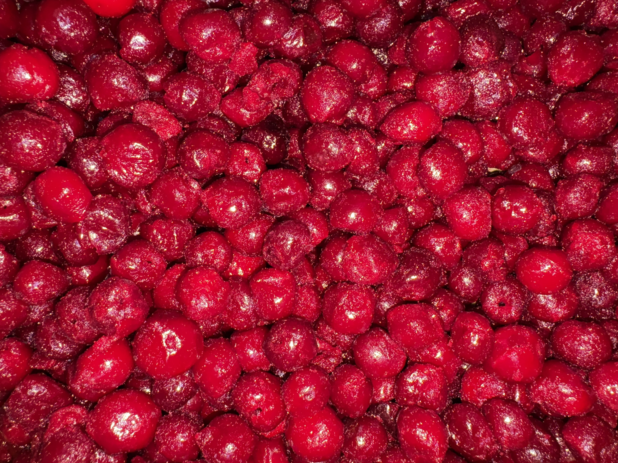 The image shows a close-up view of a large pile of bright red, dried cranberries. The cranberries are densely packed together, and their surfaces appear slightly shiny or glazed.
I cannot determine the location is Chaikovsky, Russia without location information.