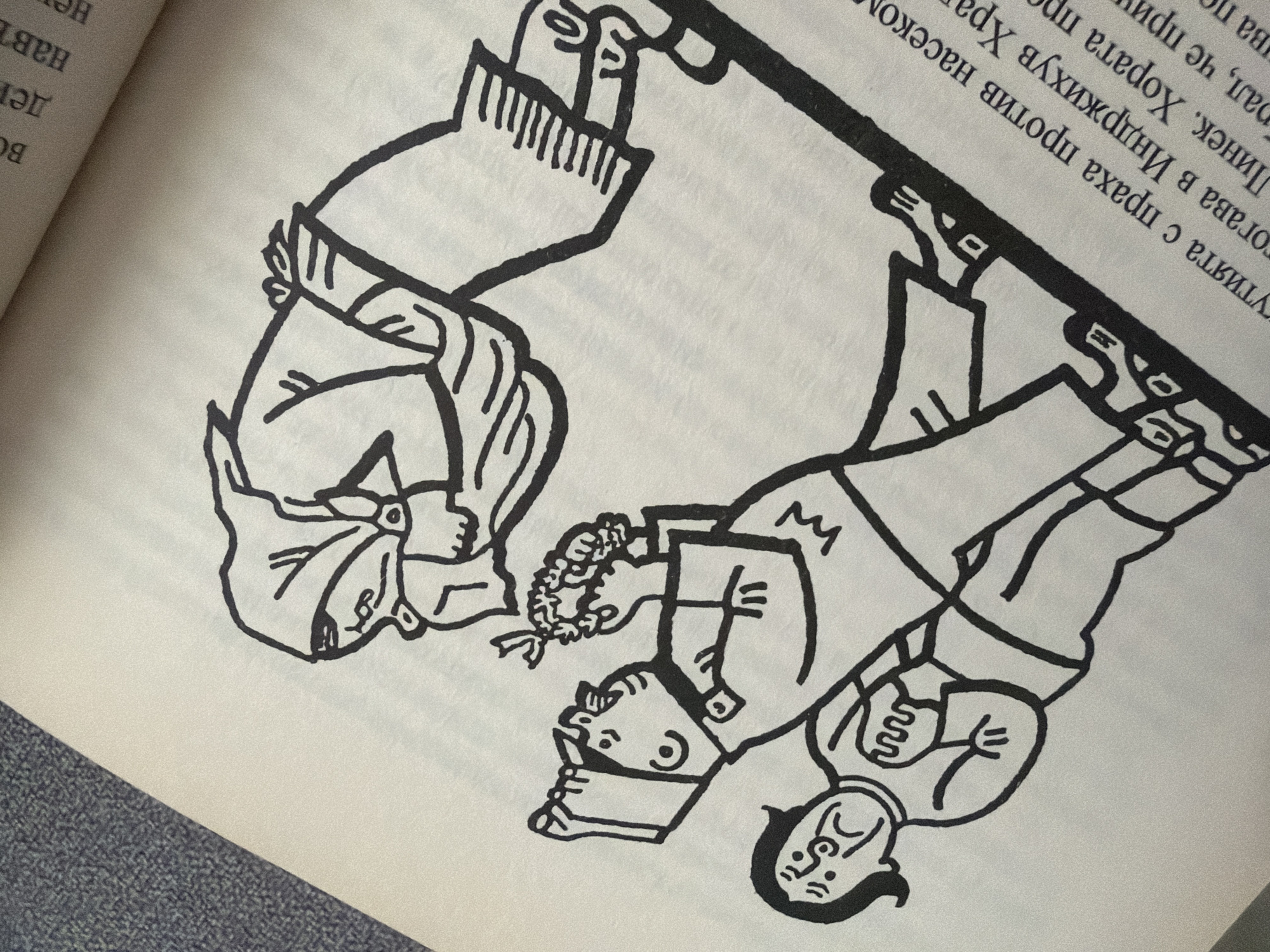 The image is a black and white drawing on a page of a book. The drawing depicts three cartoonish figures. The largest figure is standing on the right, bending forward, wearing a headscarf and an apron. Two smaller figures are on the left. The middle figure is holding a bunch of what appears to be grapes and is looking towards the larger figure. The smallest figure is in the foreground, facing left, with a distressed expression. The figures are drawn with bold outlines. There is text in Cyrillic script below the drawing. The book page is angled, with a textured grey area to the left. The drawing is in the style of a satirical illustration. There is no indication of the city of Pazardzhik, Bulgaria within the image itself or the provided text.