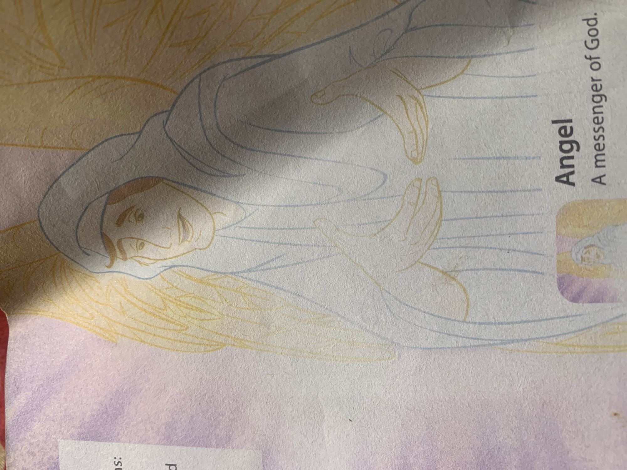 The image is a close-up photograph of an illustration of an angel, with text below that reads "Angel A messenger of God." The illustration is done in light blue and yellow outlines on a textured, off-white paper with a purple gradient background on the left side. The angel is depicted with feathered wings, a hooded garment, and outstretched hands. There is a small inset image at the bottom of the illustration showing a figure in a hooded robe. The photograph captures a portion of a book or pamphlet. The image does not contain any information about the city of Jauro Yinu, Nigeria.