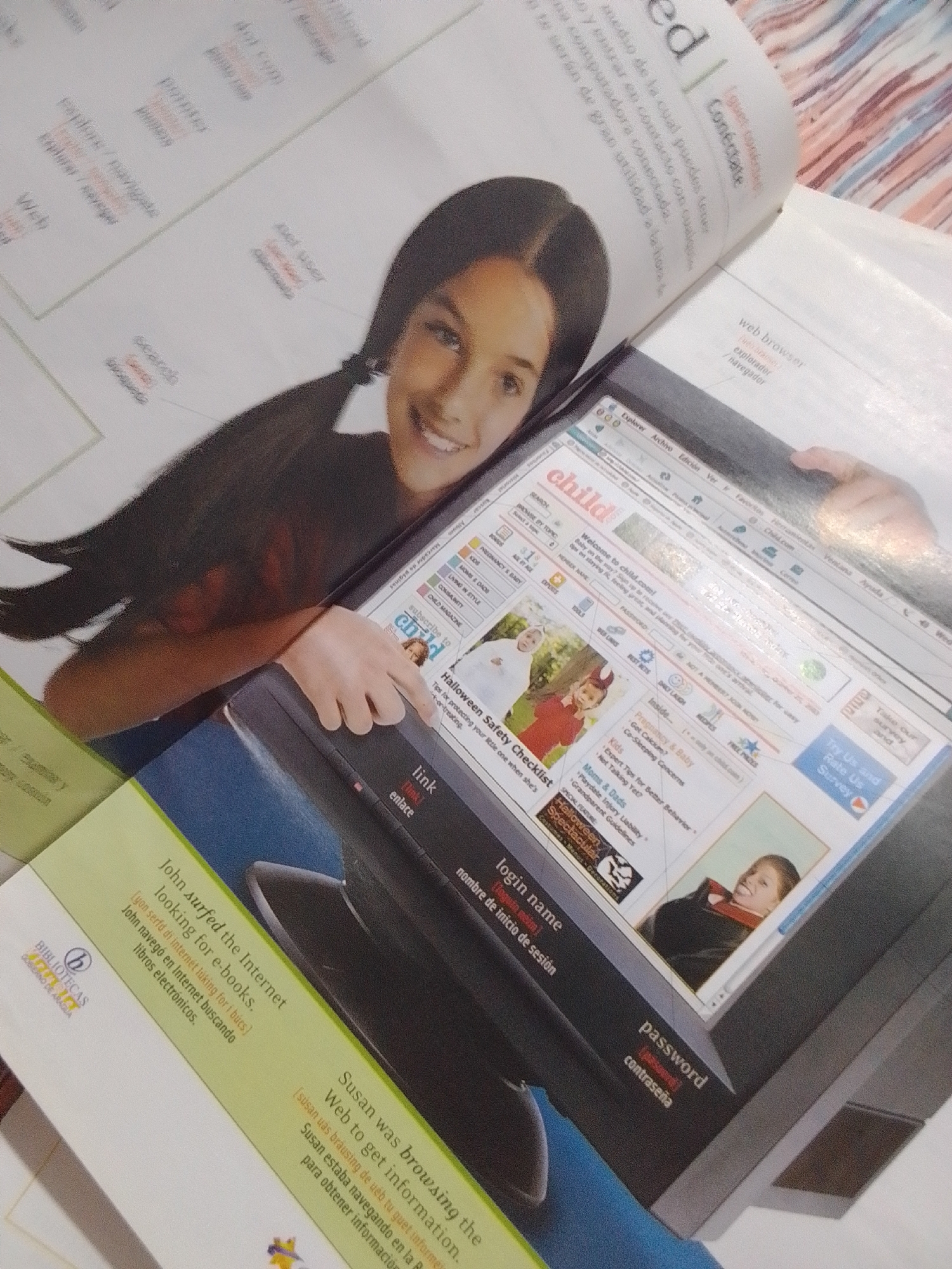 This media file is a close-up, slightly angled shot of an open book, showcasing its content and a young girl's face. The book appears to be a bilingual publication, likely an educational resource, as evidenced by the English and Spanish text. One page features a girl with dark hair styled in pigtails, smiling directly at the camera. Her face is the dominant element in the foreground of this page.
The book's content is a mix of text and images. One prominent image is a screenshot of a website titled "child.com," displaying various sections like "Pregnancy & Baby," "Kids," "Moms & Dads," and "Halloween Safety Checklist." There's also text related to logging in and passwords, suggesting the book discusses internet usage. Phrases like "John surfed the Internet looking for e-books" and "Susan was browsing the Web to get information" indicate the theme is online activities.
Another page of the book, visible in the background, has Spanish text, including "Conectate" (Connect) and "Explorador / Navegador" (Explorer/Navigator), further reinforcing the internet theme. The overall scene is indoors, likely a home or library setting, with the warm, diffused lighting suggesting it could be daytime. The girl's expression is cheerful, conveying a sense of engagement and happiness. The book itself is a physical object, open and lying flat, with the pages slightly curved. The inclusion of "BIBLIOTECAS GOBIERNO DE ARAGUA" suggests a connection to public libraries in Aragüa, Venezuela.