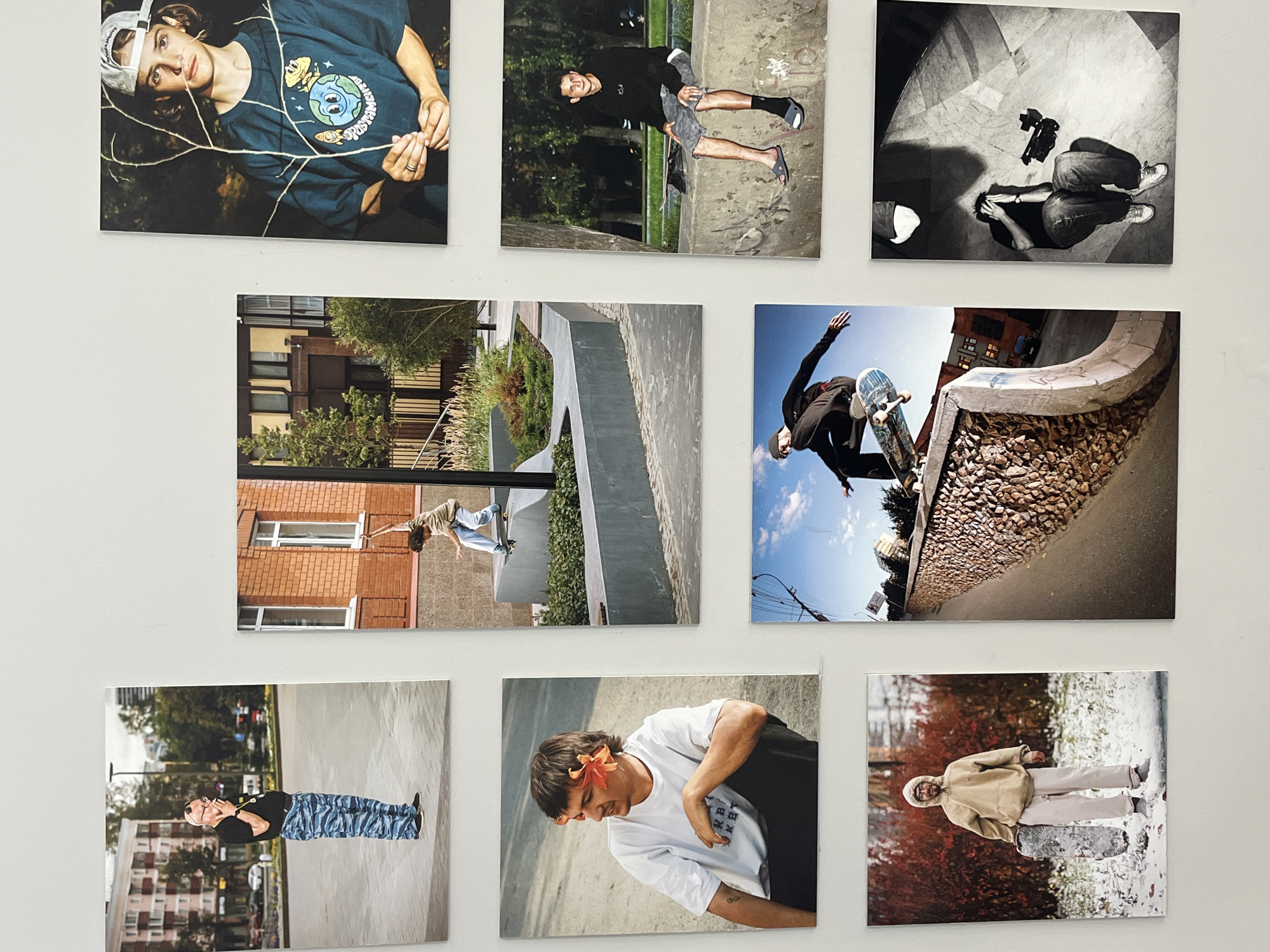 Nine square photographs are arranged in a 3x3 grid on a white wall. The images feature people, landscapes, and skateboarding scenes. They appear to be prints from a photo shoot or project. The location cannot be verified to be in Krasnoyarsk, Russia, based on the images provided.
