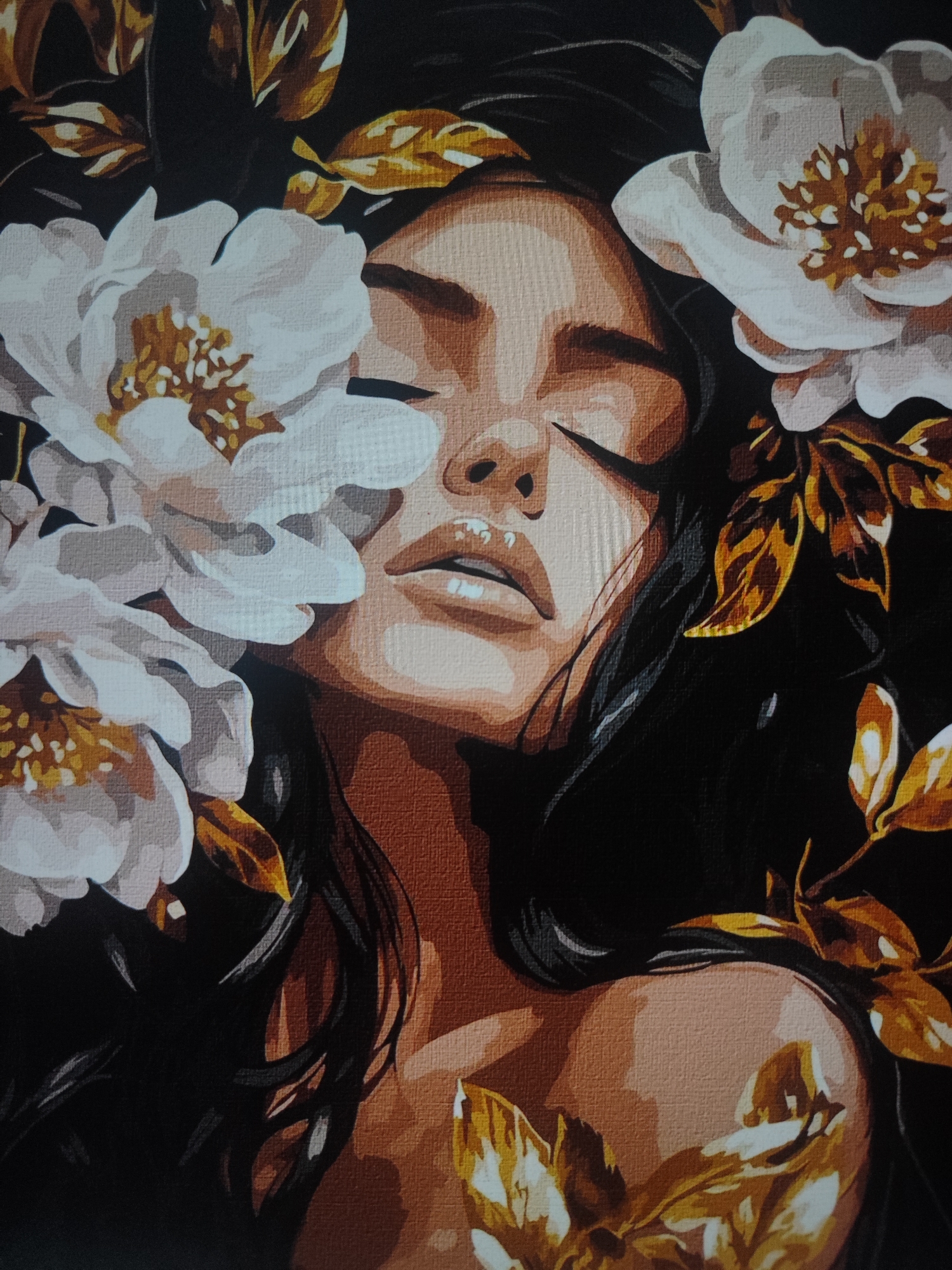 This image is a painting of a woman's face with her eyes closed, surrounded by white and golden flowers and leaves. The painting has a textured appearance, suggesting it may be a print on canvas or a textured paper. The woman has dark hair and her skin tone is depicted with shades of brown and peach. The lighting is dramatic, with strong contrasts between light and shadow. The style of the painting is somewhat stylized, with bold outlines and flat areas of color. There is no indication of a specific location in Fergana City, Uzbekistan, as the image is a close-up of a painting and not a photograph of a real-world scene.