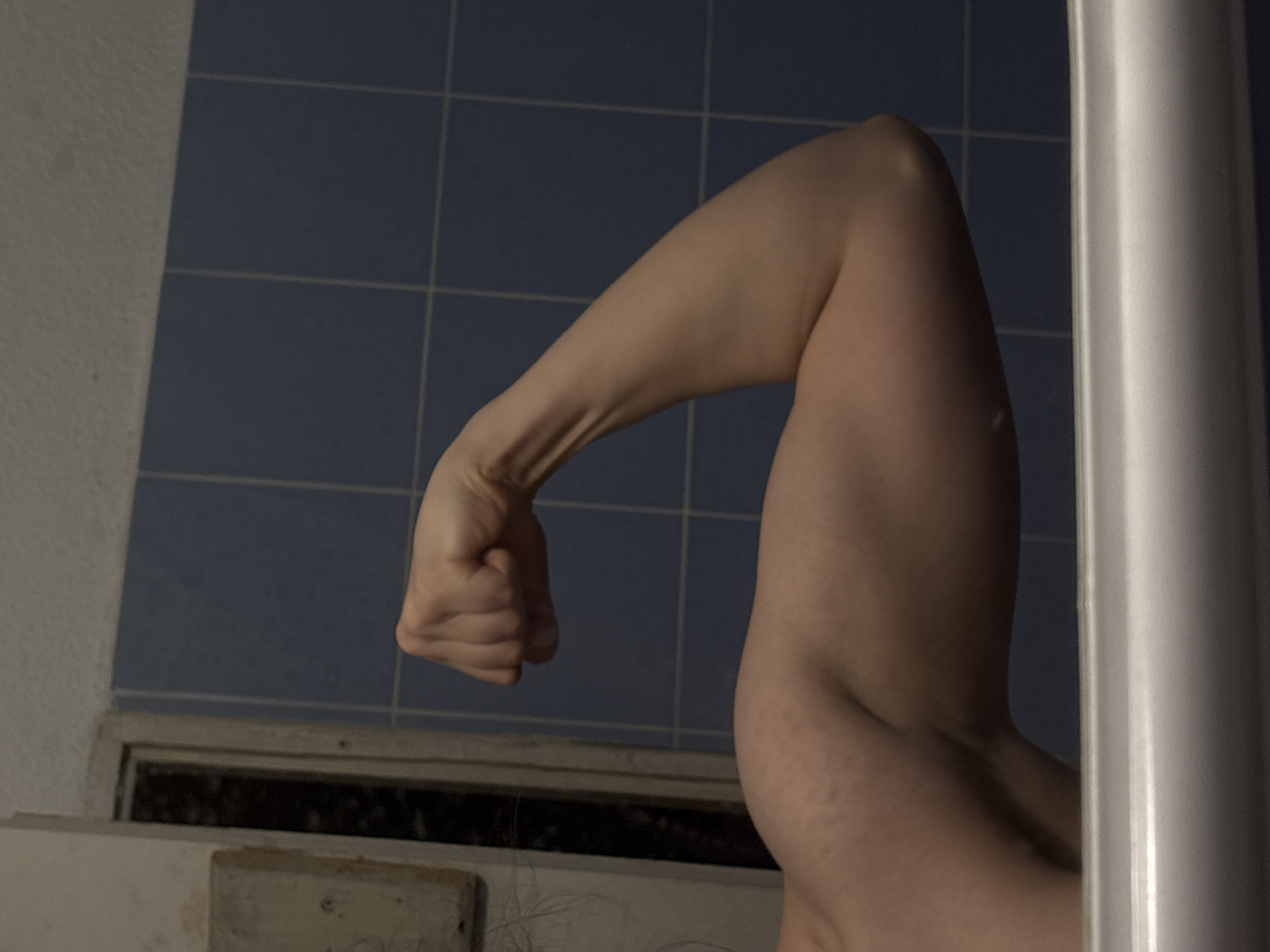An arm flexed in a bathroom with blue tiled walls. The exact location in Sofia, Bulgaria cannot be determined from the image.
