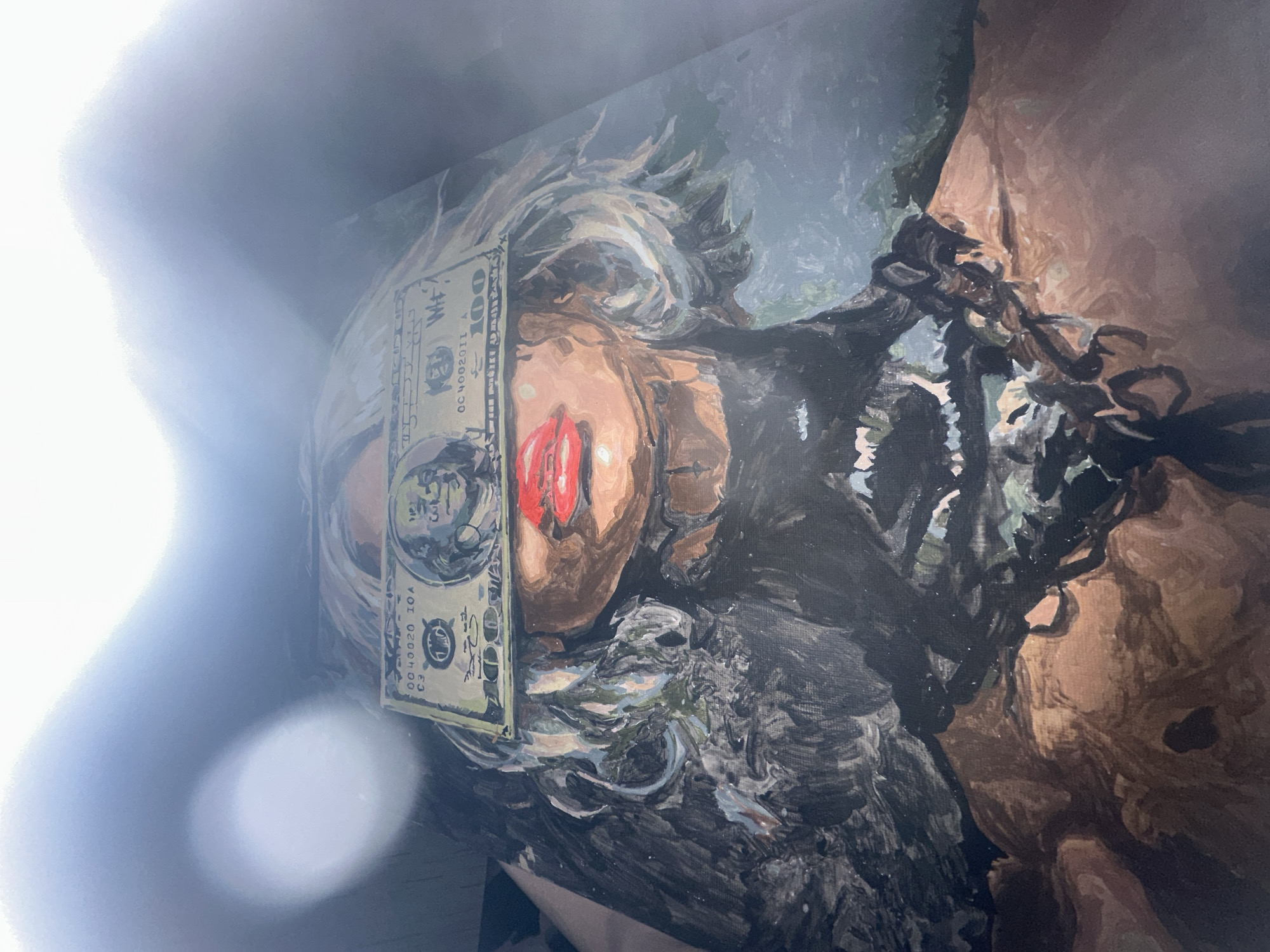A painting depicts a reclining figure with a hundred-dollar bill covering part of its face. The figure has red lipstick and appears to be bound by chains. The background has dark, indistinct features. There is a bright light reflecting into the camera in the top left corner. The painting does not appear to be located in Высокий, Russia.