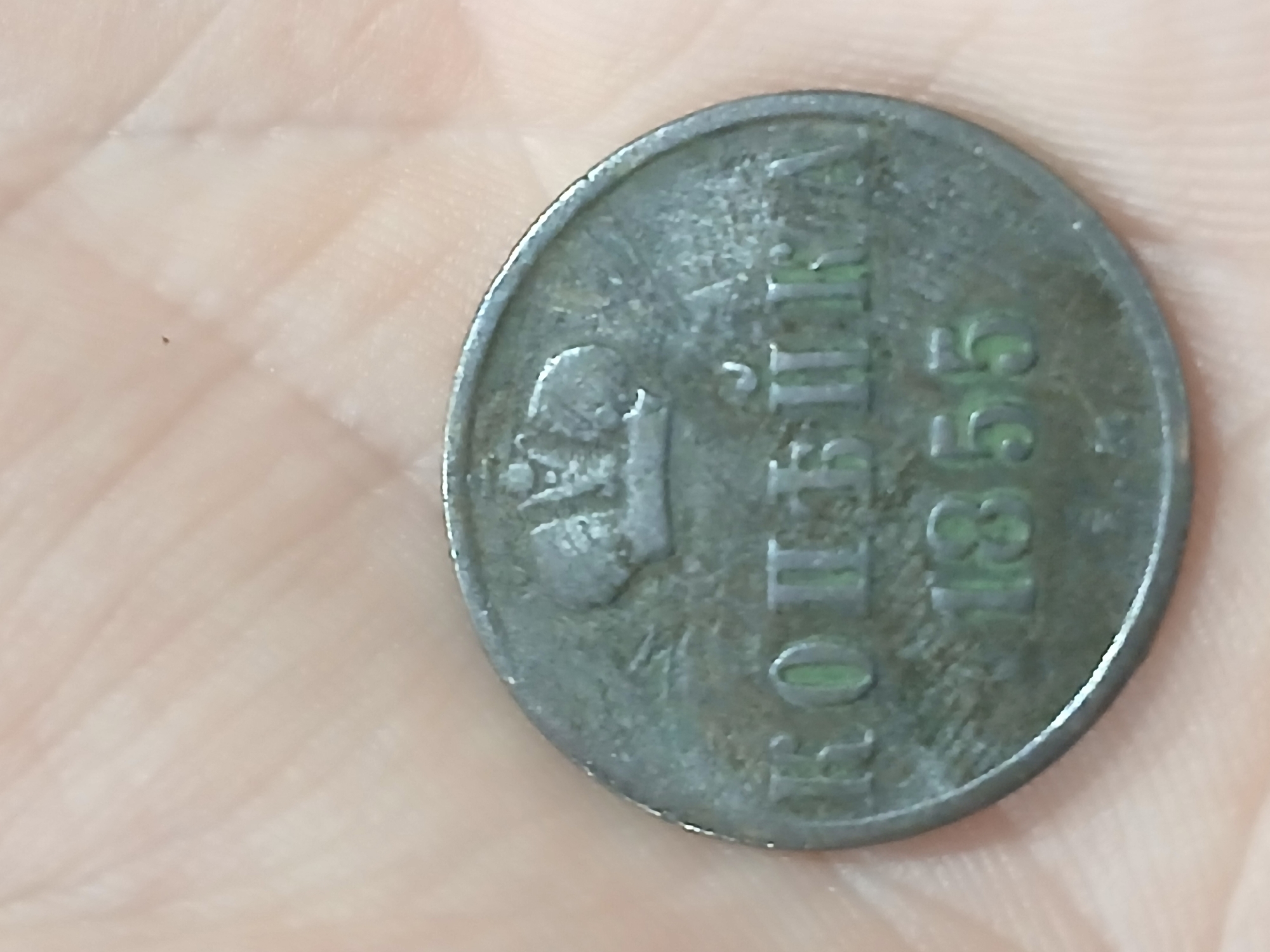 A slightly tarnished copper coin is resting on a human palm. The coin features a crown-like emblem above the Cyrillic word "КОПЕЙКА" and the date "1855" underneath. The image provides no information regarding the location in Kamianske, Ukraine.