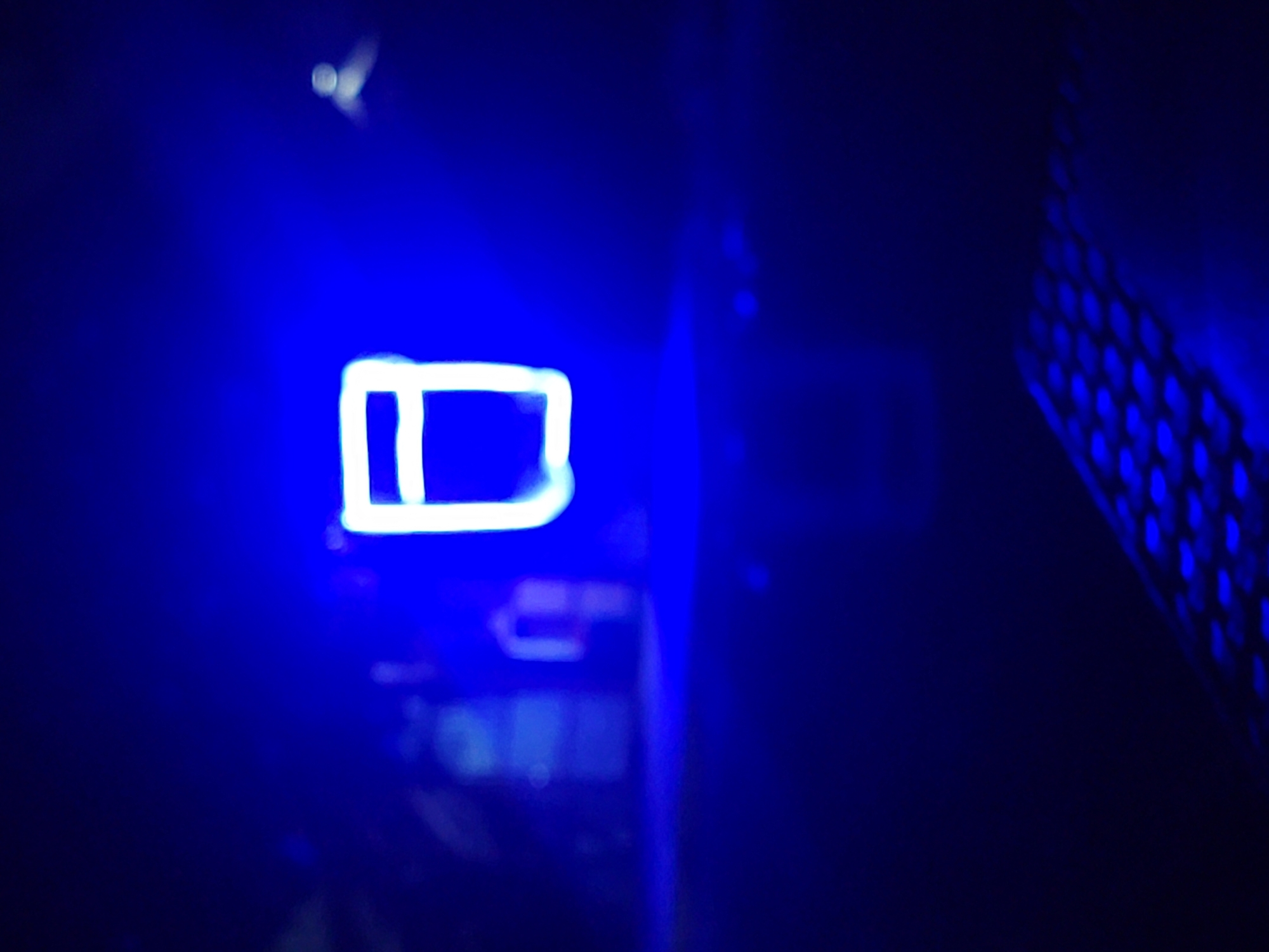The image shows the interior of a computer case, illuminated with blue light. The case's ventilation grill is visible on the right. A rectangular, neon-like light appears to the left of the center, with some computer components visible dimly below. The scene is dark, with most details obscured. There is no information in the image to indicate a specific location, let alone Barden Yana, Nigeria, or any people, actions, or interactions. The provided context cannot be confirmed.