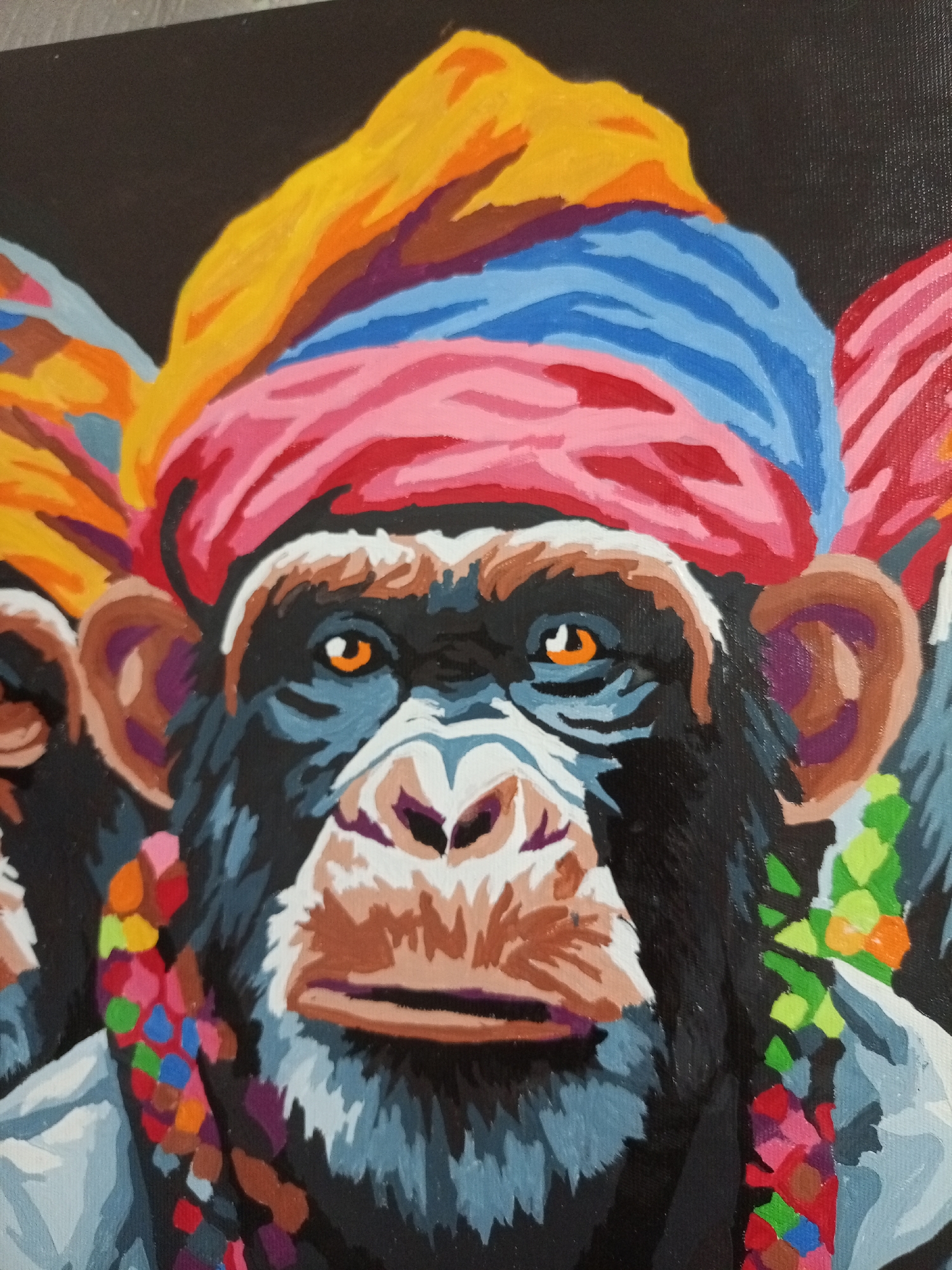 A close-up, eye-level, full-color painting depicts the faces of three chimpanzees wearing colorful turbans and necklaces. The central chimpanzee is the most prominent, positioned in the foreground. The turbans are composed of bands of yellow, orange, blue, and pink. The necklaces appear to be made of multicolored beads, including red, green, and blue. The chimpanzees are set against a dark background. The environment is unspecified. The city and location are unknown.