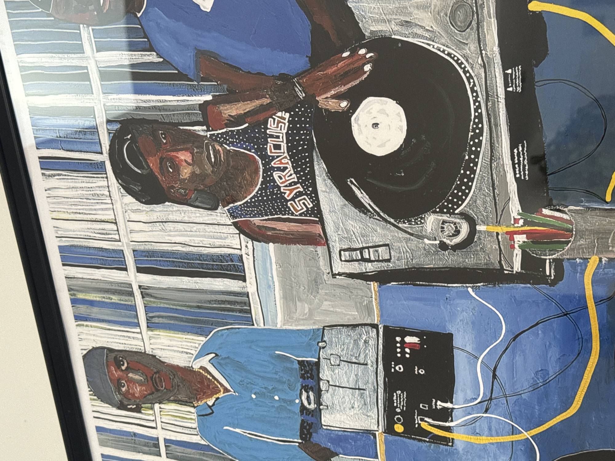 A painting depicting two figures with DJ equipment, seemingly a turntable and a mixing console. One figure wears a Syracuse jersey and headphones, hands positioned as if manipulating a record on the turntable. The other figure is in a blue outfit, adjacent to the mixing console. The painting has a textured, somewhat crude style. The background consists of horizontal stripes of blue and white. The artwork is framed. There are no indicators of London, UK.