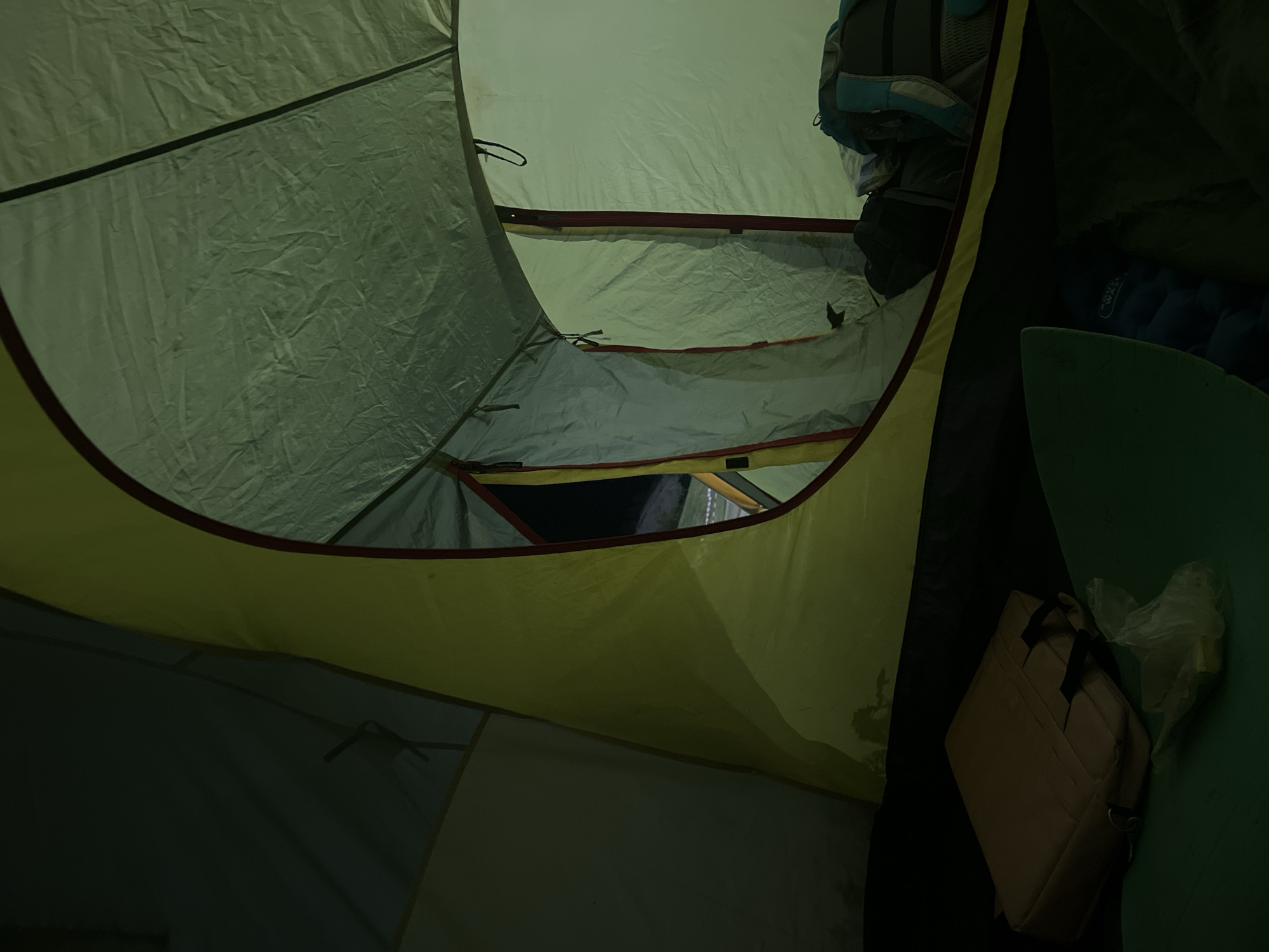 The image shows the interior of a tent, possibly a camping tent, due to the presence of camping gear such as a backpack, sleeping pad, and what appears to be a travel bag or organizer. The tent itself is made of fabric, likely nylon or polyester, with a yellow and red trim around the edges of the opening. The inside is relatively dark. There are no people visible in the image. The location is reported to be in the city of Khvalynsk, Russia, but this cannot be verified solely from the visual information in the image.