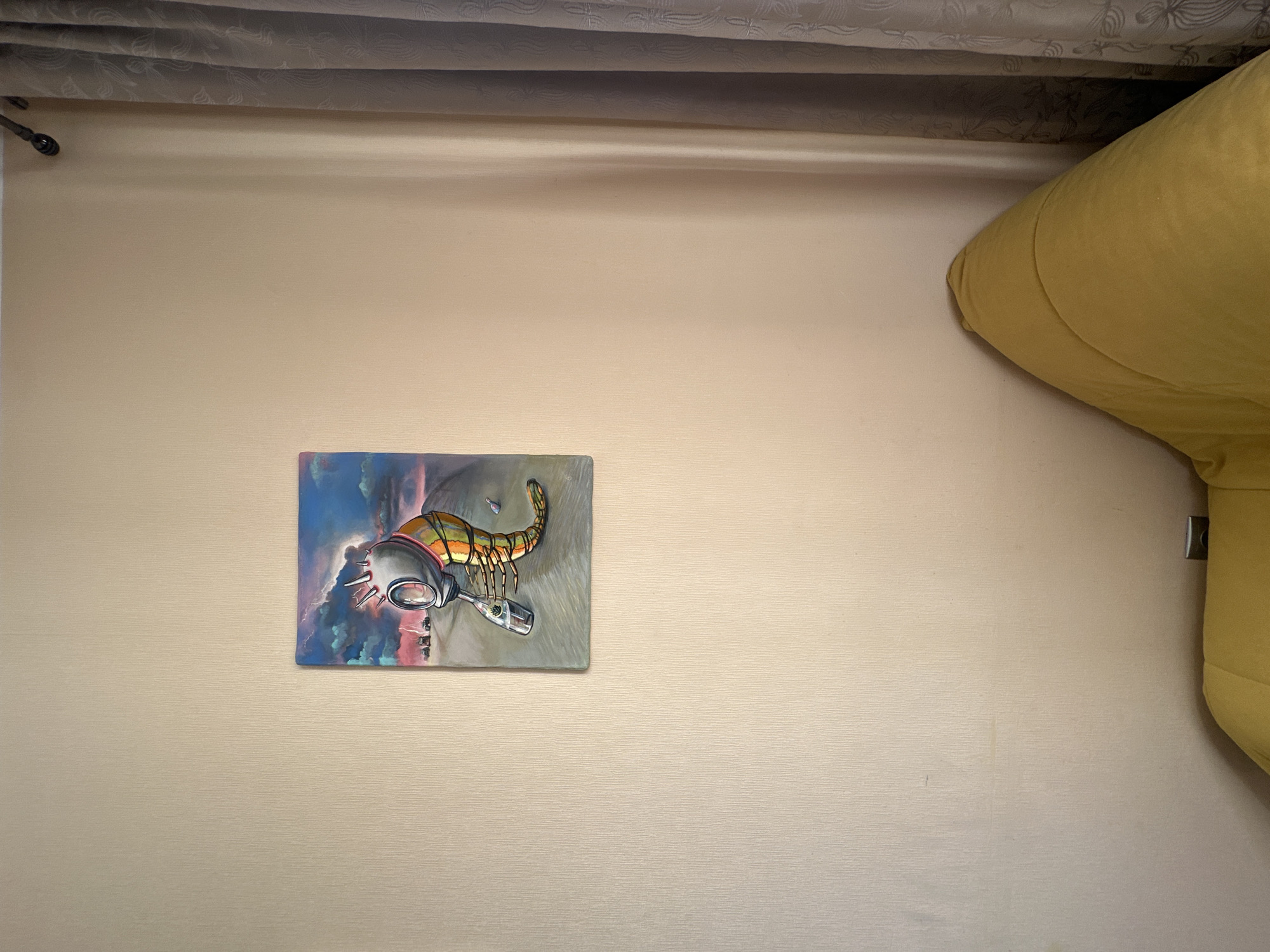 The image shows a surreal painting hanging on a textured, light-colored wall. The painting depicts a creature with a gas mask-like head and a segmented, colorful body, holding a bottle with green foliage inside. In the background of the painting, there is a stormy sky with lightning, a desolate road, and several vehicles. To the right of the painting, a grey curtain with a floral pattern is visible, and a corner of a yellow beanbag chair is in the bottom right of the frame. The scene appears to be an interior space, possibly a room in Saint Petersburg, Russia, given the context.
