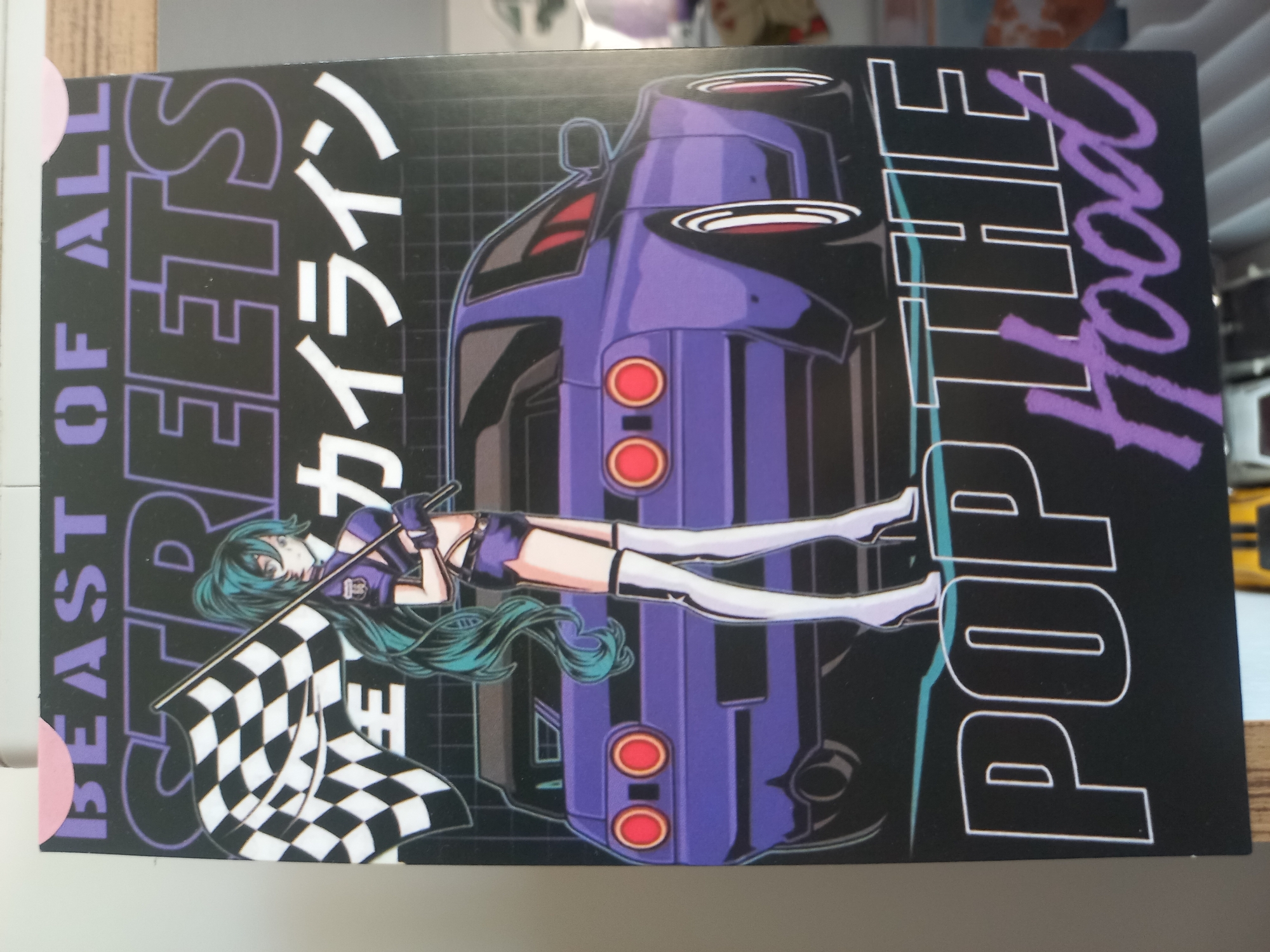 A sticker depicts an anime-style woman with long teal hair holding a checkered flag and standing next to a purple car. The car appears to be a Nissan Skyline R32. Text on the sticker reads "BEAST OF ALL STREETS" in stylized lettering, with Japanese characters and "POP THE HOOD" in a script font. The sticker is not located in Parvomay, Bulgaria, as there are no visible geographical indicators to support this claim.