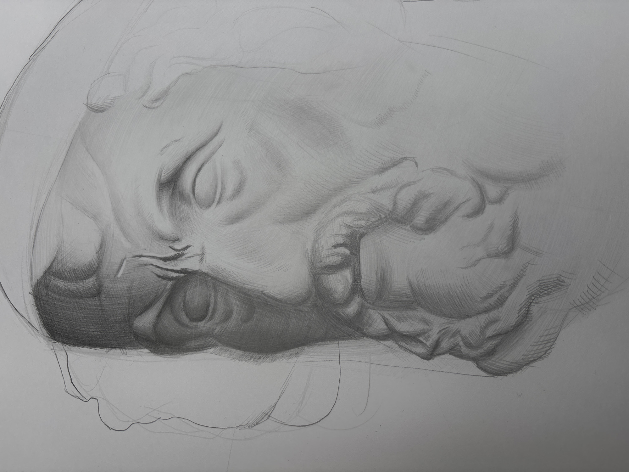 The image depicts a detailed pencil drawing of a male head in profile, lying on its side. The figure's eyes are closed, and the facial features are heavily shadowed around the nose and beard. The hair is suggested with lightly sketched lines. An underdrawing is faintly visible outlining the head and the area around it. The drawing is on white paper. The environment is a blank background. There are no people or objects in the immediate surrounding area. The image does not contain information to determine if this is in the city of Yerevan, Armenia.