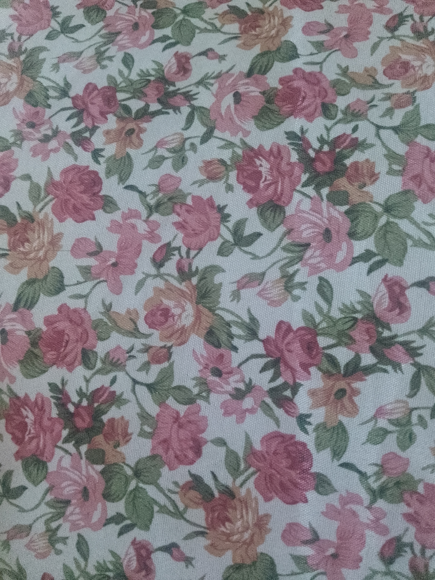 The image shows a fabric with a floral pattern. The pattern consists of various pink and peach-colored roses and smaller flowers, interspersed with green leaves. The background is a light, possibly off-white, color. The fabric appears to be a woven material. There is no discernible information to suggest the location of the image being in Davao City, Philippines. There are no people, actions, interactions, or environment elements to describe beyond the fabric itself.