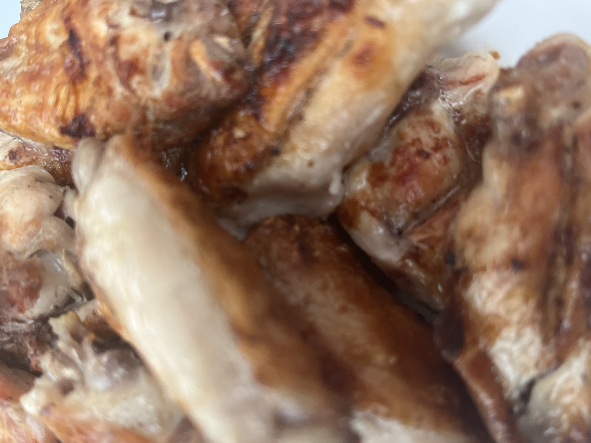 A close-up shot of cooked chicken pieces. The chicken is grilled, showing brown marks and a golden-brown color. The pieces are piled together, making it difficult to distinguish individual parts. No location information or other contextual details are discernible from the image.