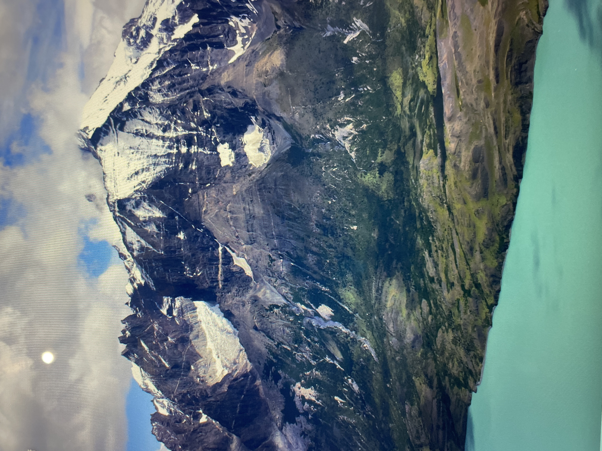 The image shows a mountain range next to a body of water. The mountains are rocky and covered in snow and vegetation. The body of water is a turquoise color. The image is not from Mexico City, Mexico.