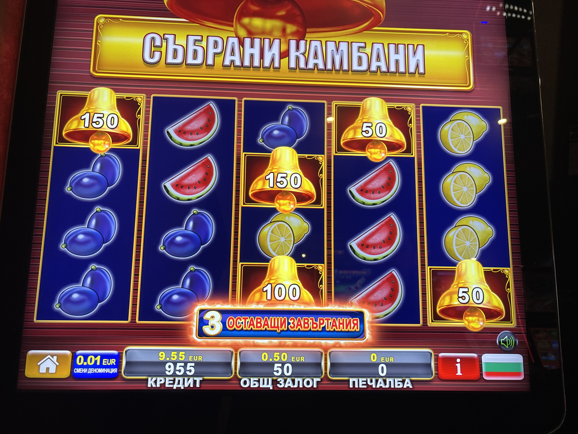 The image shows a slot machine screen, likely located in Sofia, Bulgaria, given the Bulgarian flag on the bottom right. The game title is "СЪБРАНИ КАМБАНИ," which translates to "Collected Bells." The reels display various symbols, including bells with values (150, 50, 100), plums, watermelons, and lemons. The screen indicates the player has 3 remaining spins ("3 ОСТАВАЩИ ЗАВЪРТАНИЯ"). The credit balance is 9.55 EUR/955, and the total bet is 0.50 EUR/50. There are no current winnings displayed ("0 EUR"). Control buttons are visible at the bottom of the screen.