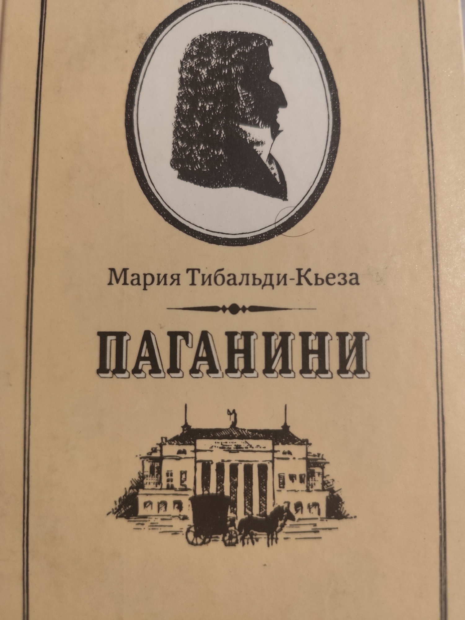 The image is a close-up of a book cover with a light beige background. At the top, there is a circular black and white silhouette of a man's profile with curly hair. Below the silhouette, in dark gray text, is the author's name: "Мария Тибальди-Кьеза". Centered below the author's name, in large, bold, black letters with white outlines, is the title "ПАГАНИНИ". Beneath the title, a black silhouette depicts a building with columns and a carriage pulled by two horses, suggesting a historical or artistic theme. There is no information in the image to indicate its location in Aqbulaq Rural District, Kazakhstan.