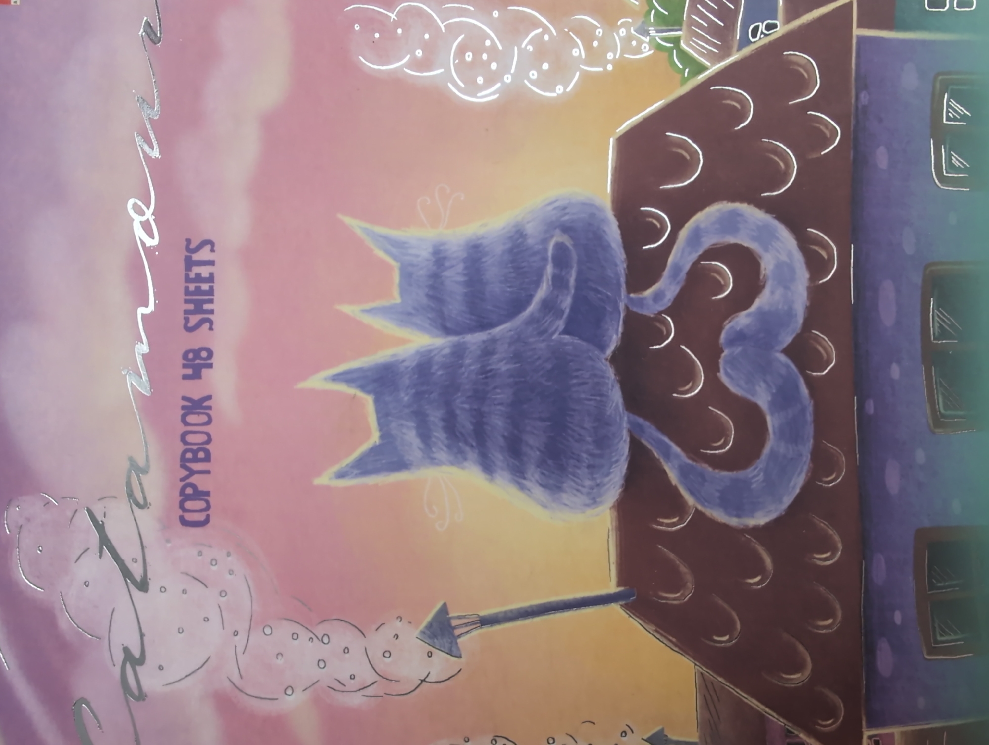 The image displays a whimsical illustration, likely the cover of a copybook, featuring two stylized cats on a rooftop against a vibrant gradient sky.
**Subjects:** The central subjects are two blue-purple cats with subtle darker stripes, rendered with a soft, furry texture, viewed from behind. They are seated closely, with one cat's tail elegantly curving into a heart shape. They rest on the roof of a brown building adorned with decorative white, arch-shaped patterns. To the right, part of another building in purple and blue is visible, featuring simple white-outlined windows. The background includes stylized white "clouds" or puffs, some containing small circles, enhancing a dreamy atmosphere. A dark, arrow-like object extends from the left side of the brown building.
**Activity or event taking place:** The cats appear to be resting or gazing over the cityscape, with their intertwined tails forming a heart, suggesting a moment of affection or companionship.
**Notable details:** The sky transitions from soft pinks and purples to an orange-yellow hue, indicative of either sunrise or sunset, creating a warm, ethereal ambiance. The art style is illustrative and whimsical, with reflective outlines on the cats and specific text.
**Visible text:** The text "COPYBOOK 48 SHEETS" is printed vertically in dark purple. A larger, reflective silver word, possibly "Catana" or a similar feline-themed name, runs diagonally along the left side, partially obscured by other elements.