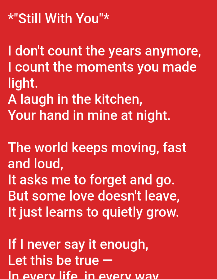 The image contains a red background with white text that appears to be lyrics to a song. The text is centered on the image and is written in a sans-serif font. The text reads:
*"Still With You"*
I don't count the years anymore,
I count the moments you made
light.
A laugh in the kitchen,
Your hand in mine at night.
The world keeps moving, fast
and loud,
It asks me to forget and go.
But some love doesn't leave,
It just learns to quietly grow.
If I never say it enough,
Let this be true —
In every life, in every way
There is no information in the image to suggest a location in Ujjain, India.