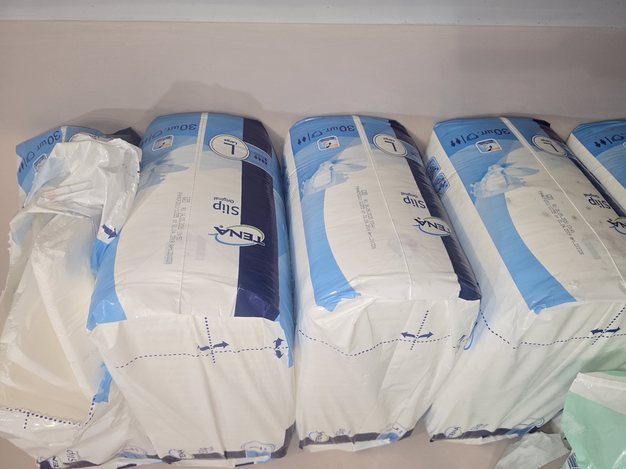 A stack of packaged adult diapers is shown. The packaging is white and blue and features the brand name "TENA Slip Original" along with the size "L" for Large. Some packages also indicate "30 шт." which means 30 pieces. The diapers are likely in a store or warehouse environment. The image does not provide any information about the city of Ulan-Ude, Russia.