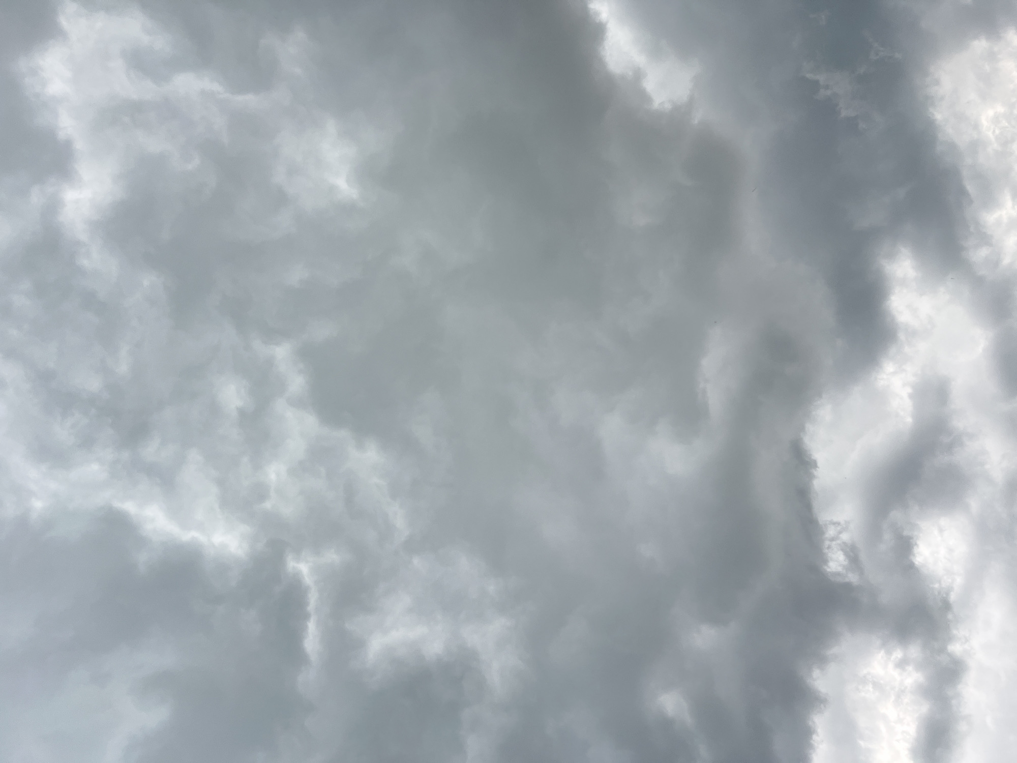 A sky filled with overcast, dark gray clouds, with some patches of lighter gray and white. The clouds are varied in texture and density, creating a sense of depth and movement. There is no visible sky other than clouds. The scene is a close-up, full-frame shot of the sky.