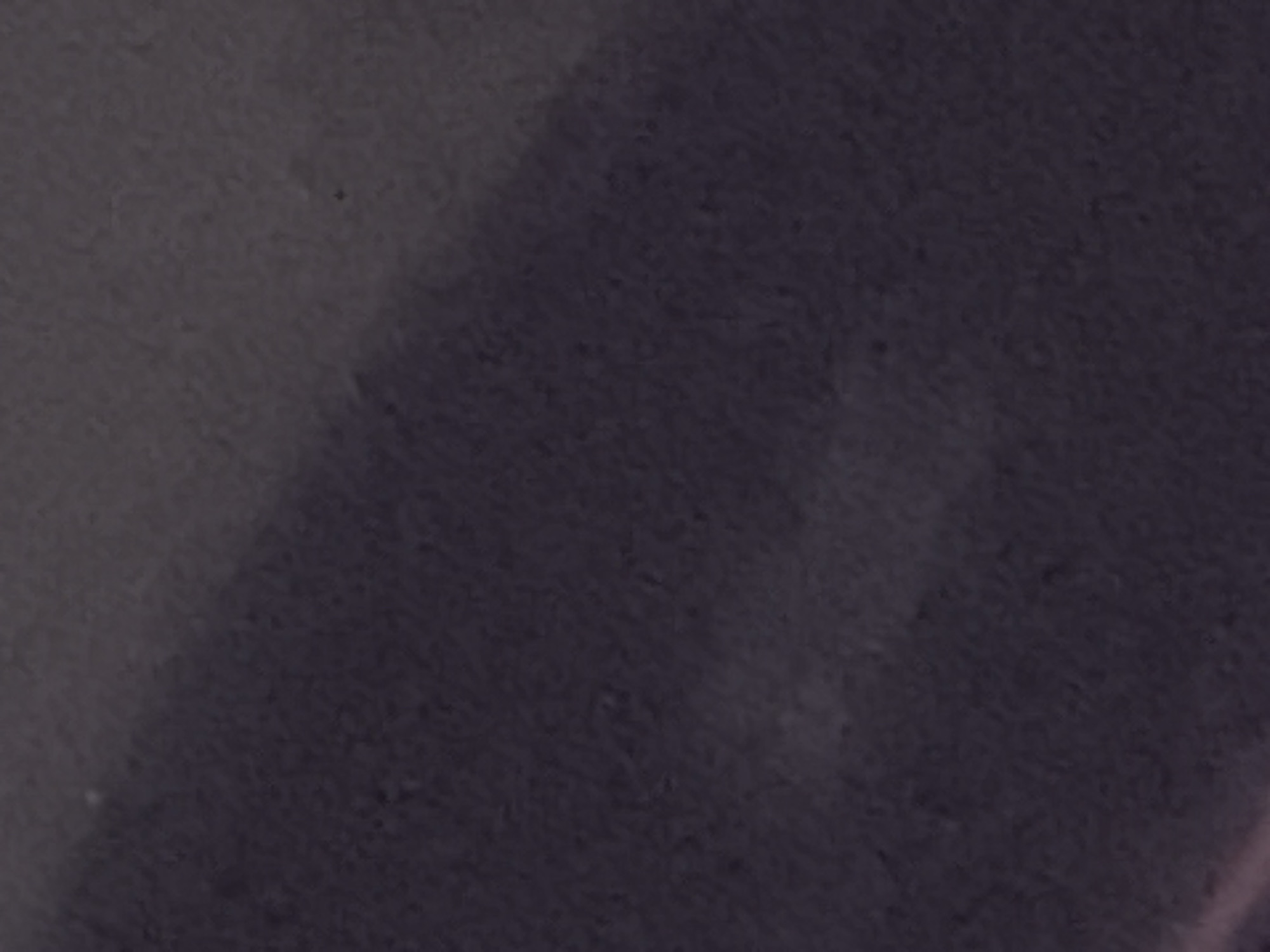 The image presents a close-up view of a textured surface, potentially a wall or fabric. The predominant colors are shades of gray, ranging from light to dark, creating variations in tone and depth. The surface appears slightly uneven with subtle imperfections, giving it a tactile quality. The location of the image cannot be determined to be in Sofia, Bulgaria, based on the visual information provided.