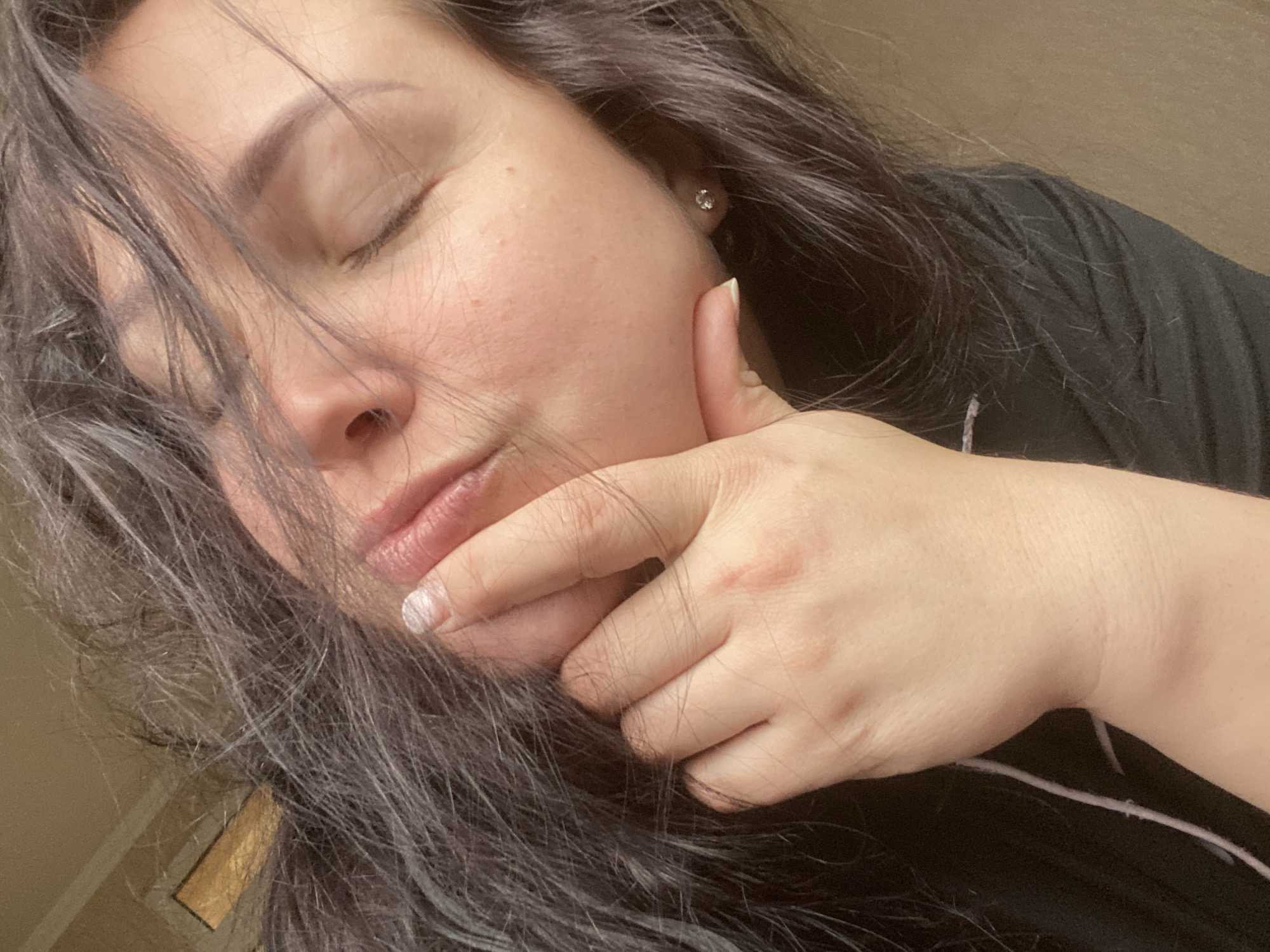A woman with dark hair is seen from a low angle, with her eyes closed and her right hand supporting her chin. She is wearing a dark shirt. An earring is visible in her right ear. The location, Sochi, Russia, is not evident in the image.