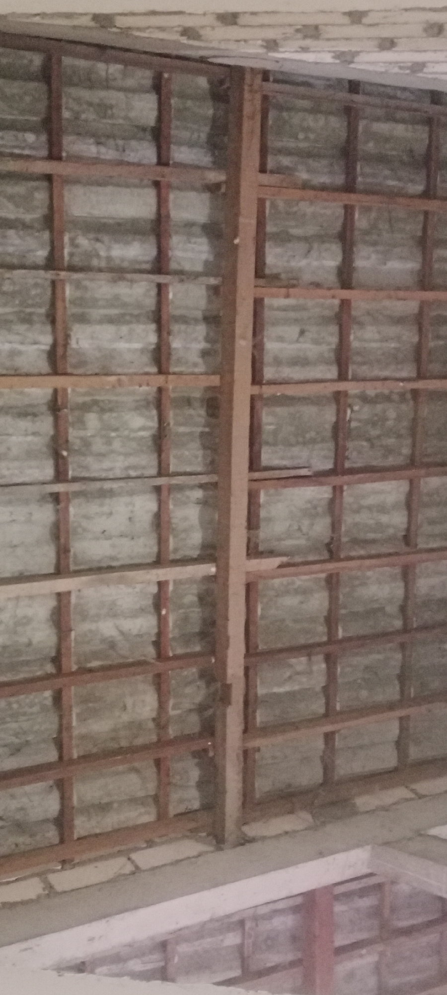 The image shows the underside of a damaged roof structure in Soko, Indonesia. The roof is composed of corrugated metal sheeting supported by a wooden lattice framework. Several beams and crossbars are visible, some of which appear to be deteriorating or missing. The overall impression is one of disrepair and potential structural weakness. The image does not contain any people or provide specific details about the location within Soko.