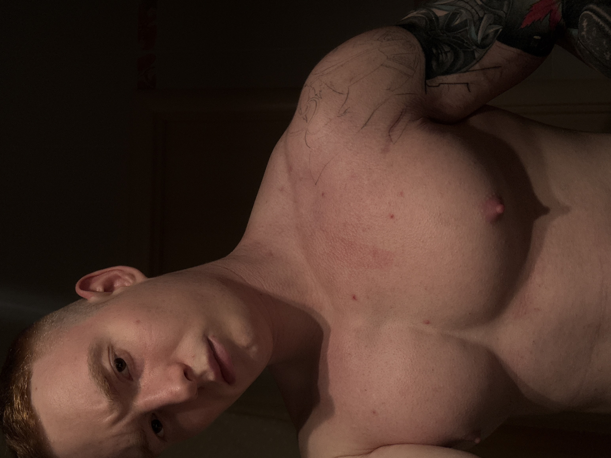 A close-up shot shows a shirtless man with fair skin and short, reddish-brown hair. He has tattoos on his left arm. The background appears dark. There is no information available in the image to determine the location as Chaikovsky, Russia.