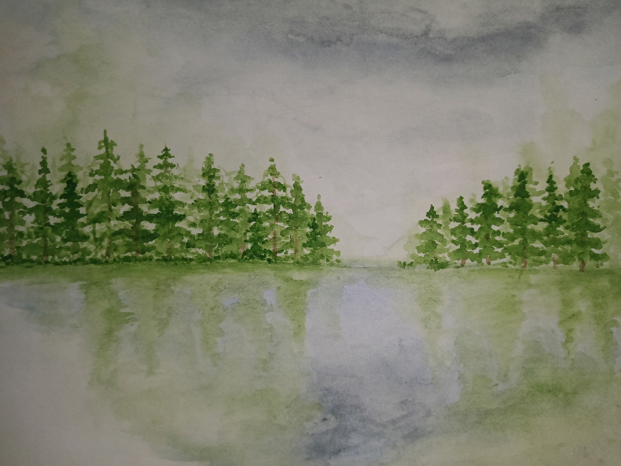 The image is a watercolor painting depicting a serene landscape. In the foreground, a body of water reflects a line of evergreen trees that form a dense forest along the opposite bank. The trees are painted in various shades of green, suggesting a thick canopy. The water's surface is rendered with muted colors, indicating stillness. In the background, the sky is overcast with soft, diffused light. The overall mood of the painting is peaceful and tranquil. There is no indication of the city of Karnal, India, or any specific location within it. The scene is devoid of people, objects, actions, or interactions, focusing solely on the natural environment.