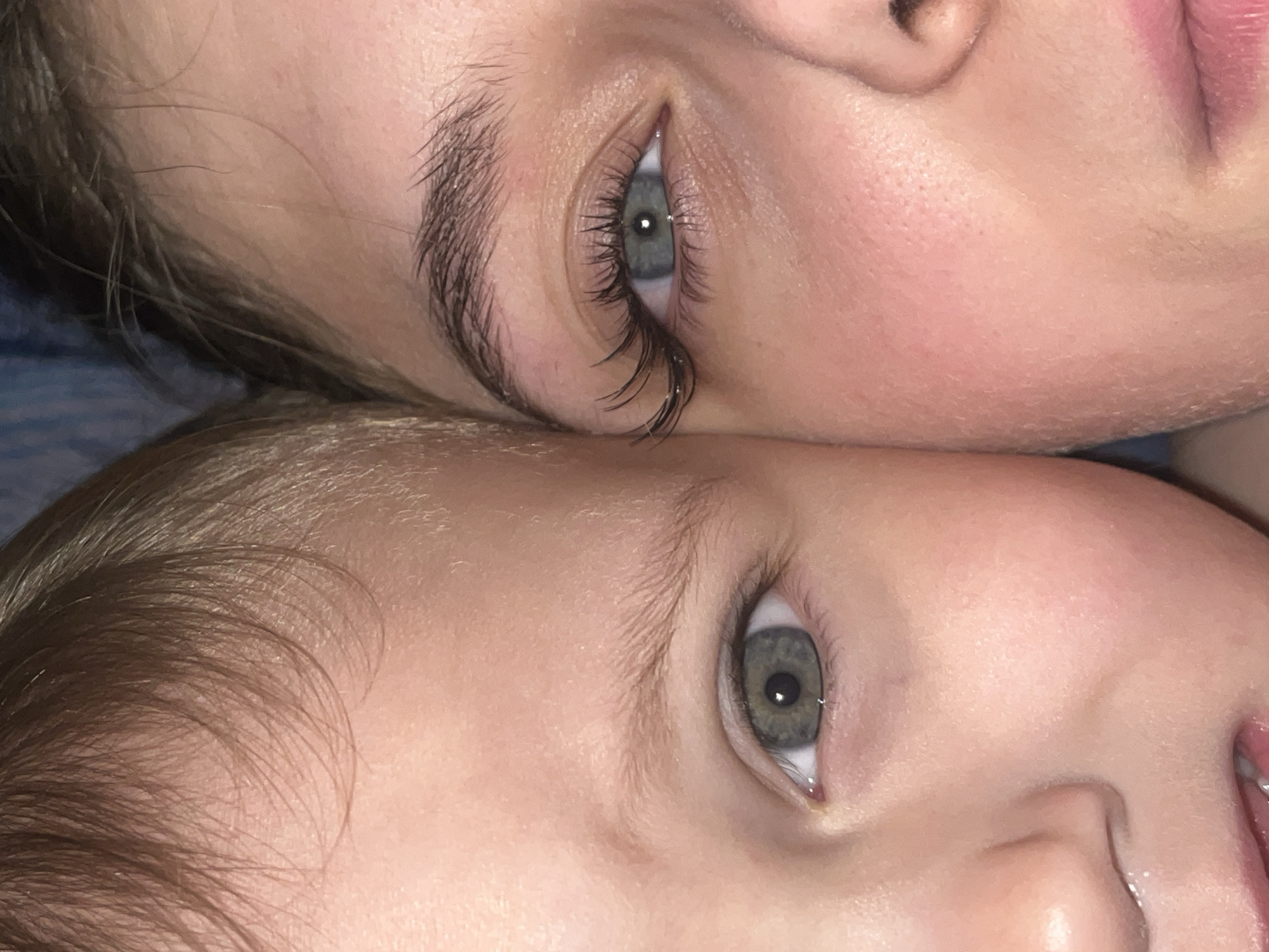 The image shows a close-up view of two faces positioned closely together, with their eyes aligned vertically. The upper face appears to be that of an adult, while the lower face seems to be that of a child. The adult has defined eyelashes and eyebrows. Both faces have fair skin tones, and the eyes are of a similar color. The image is cropped tightly, focusing on the facial features. There is no indication of location in Фоки, Russia, or any other geographical place.