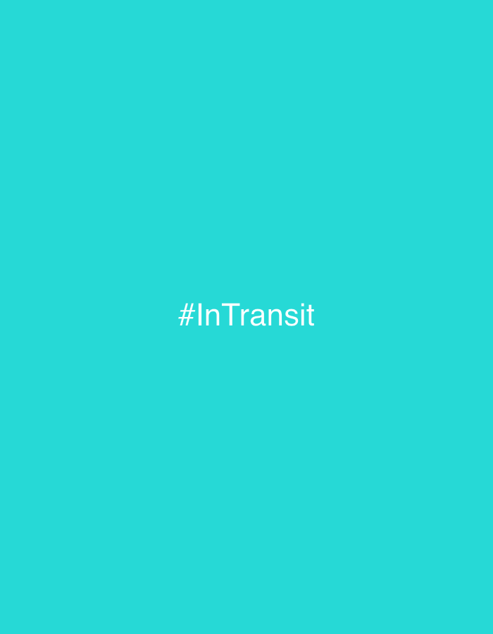 A minimalist image displays the hashtag "#InTransit" in white, sans-serif text centered against a solid, vibrant turquoise background. The background offers no discernible environmental or contextual details, making the text the sole focal point. There are no people, objects, or actions present in the scene. The image is devoid of any specific location, including Kuta Selatan, Indonesia.