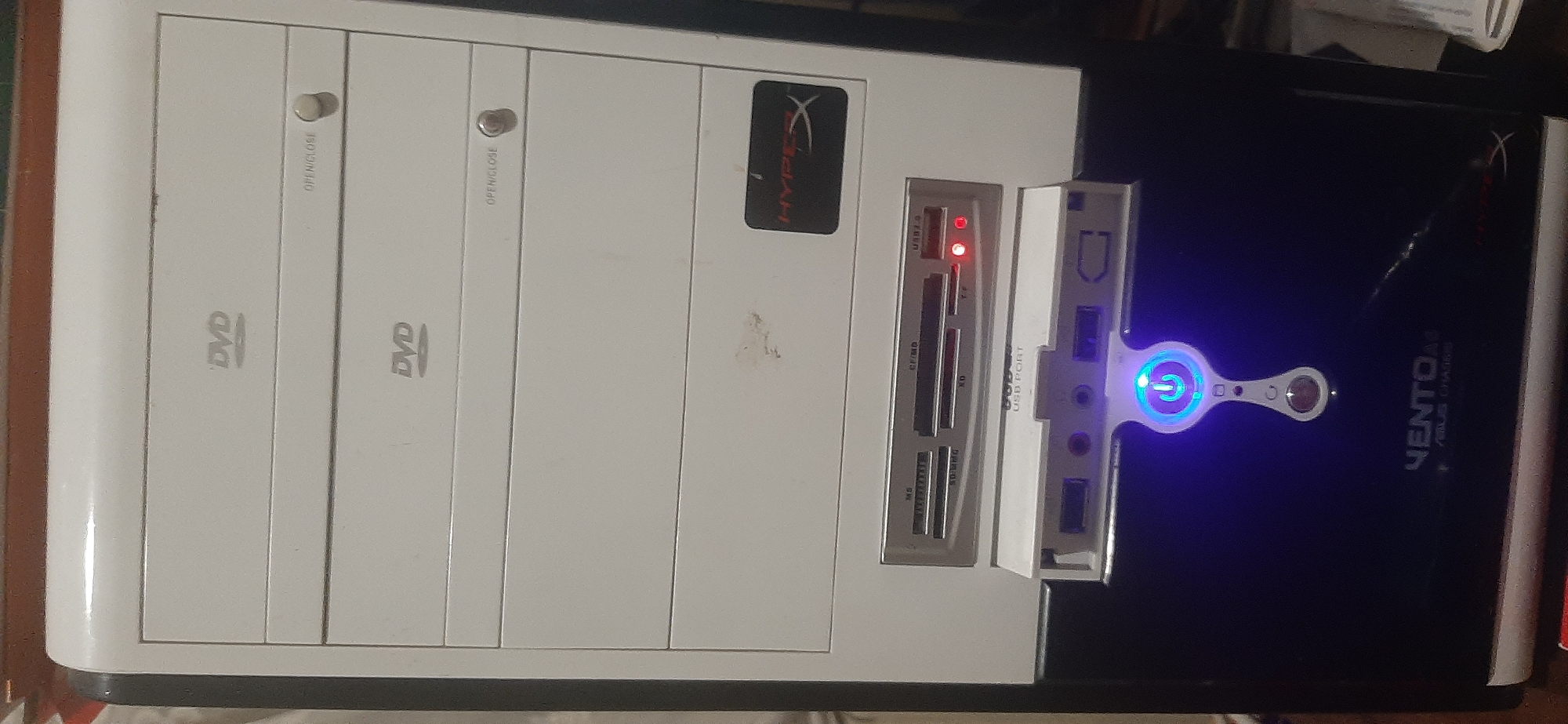 This is a close-up, eye-level shot of the front of a white and black computer tower. The tower has multiple drive bays, with two labeled "DVD". Below the drive bays is a card reader with various slots labeled for different memory card types, and a USB 3.0 port. There are also several USB ports and audio jacks visible, along with a power button that is illuminated with blue light. A red light is also visible on the card reader. A "HYPERX" sticker is on the white part of the tower, and the brand name "VENTO" is visible on the black part of the tower, below the USB ports. The image does not provide any information about the location in the city of Yessentukskaya, Russia, or any people, actions, or interactions.