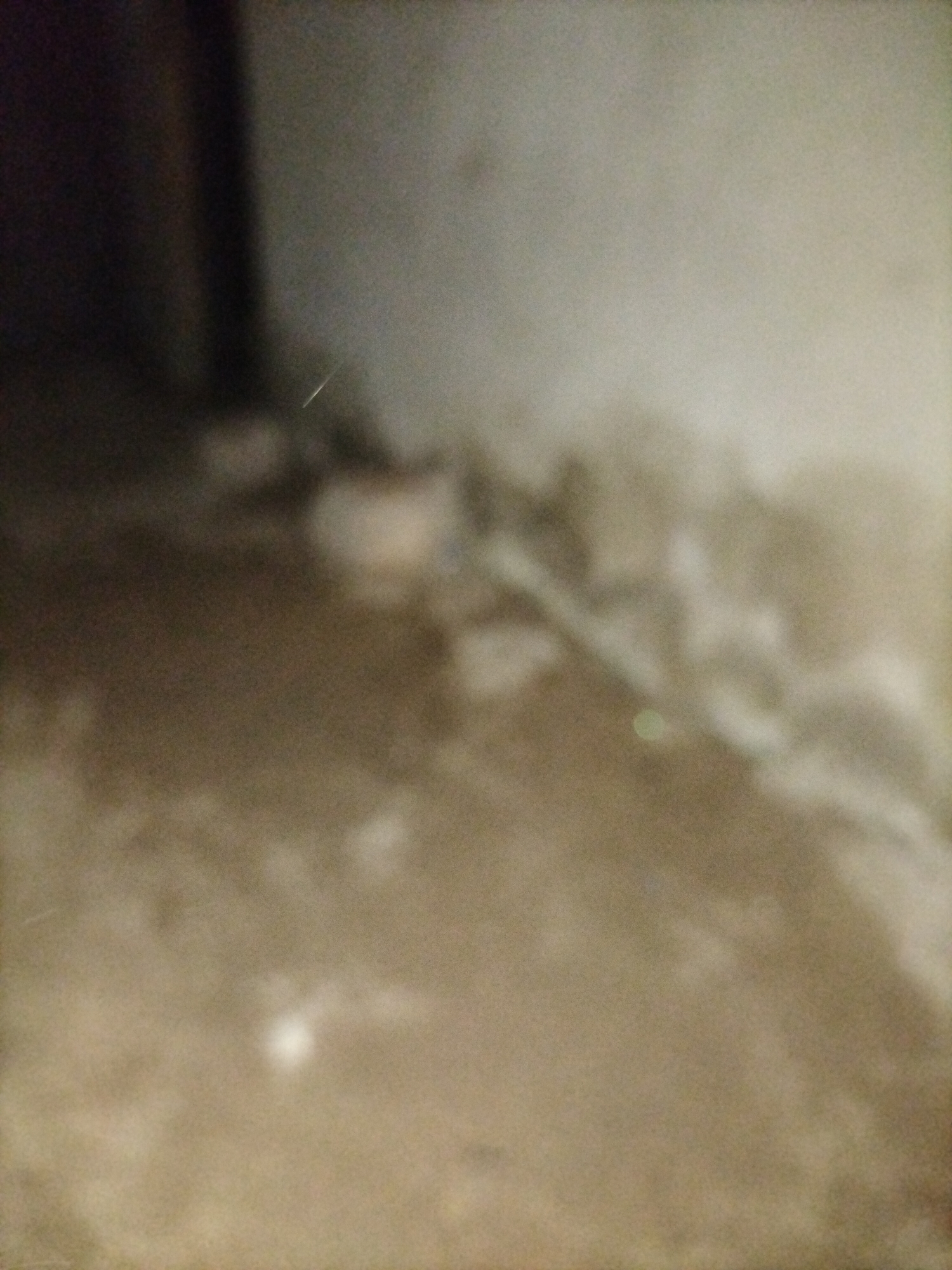 The image depicts a dimly lit interior space with a rough, textured floor. The lighting suggests artificial illumination, casting shadows and creating a hazy atmosphere. The overall impression is one of an unfinished or neglected building, possibly a construction site or an abandoned structure. The colors are muted, dominated by browns, grays, and dark tones. There are no discernible people or specific objects that can be identified with certainty due to the low quality and blurriness of the image. The scene could be anywhere, and there is no visual information to place it in Jalingo, Nigeria, or any specific city.