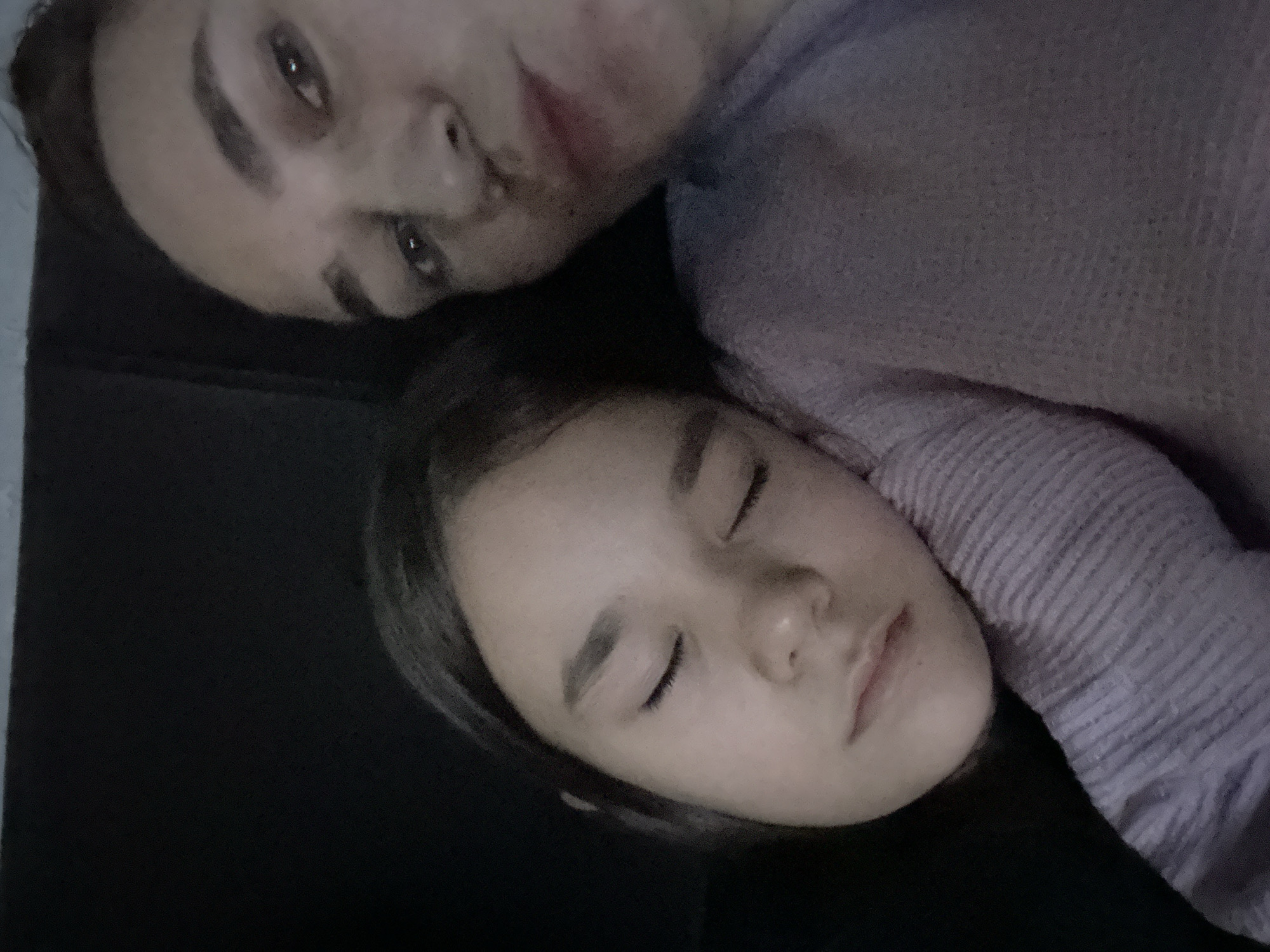 Two people are depicted in the image. The top person has their eyes open and is looking at the camera. The bottom person has their eyes closed. The two appear to be lying down together. The scene does not appear to be set in a specific location. The location in the city of Uva, Russia is not evident.