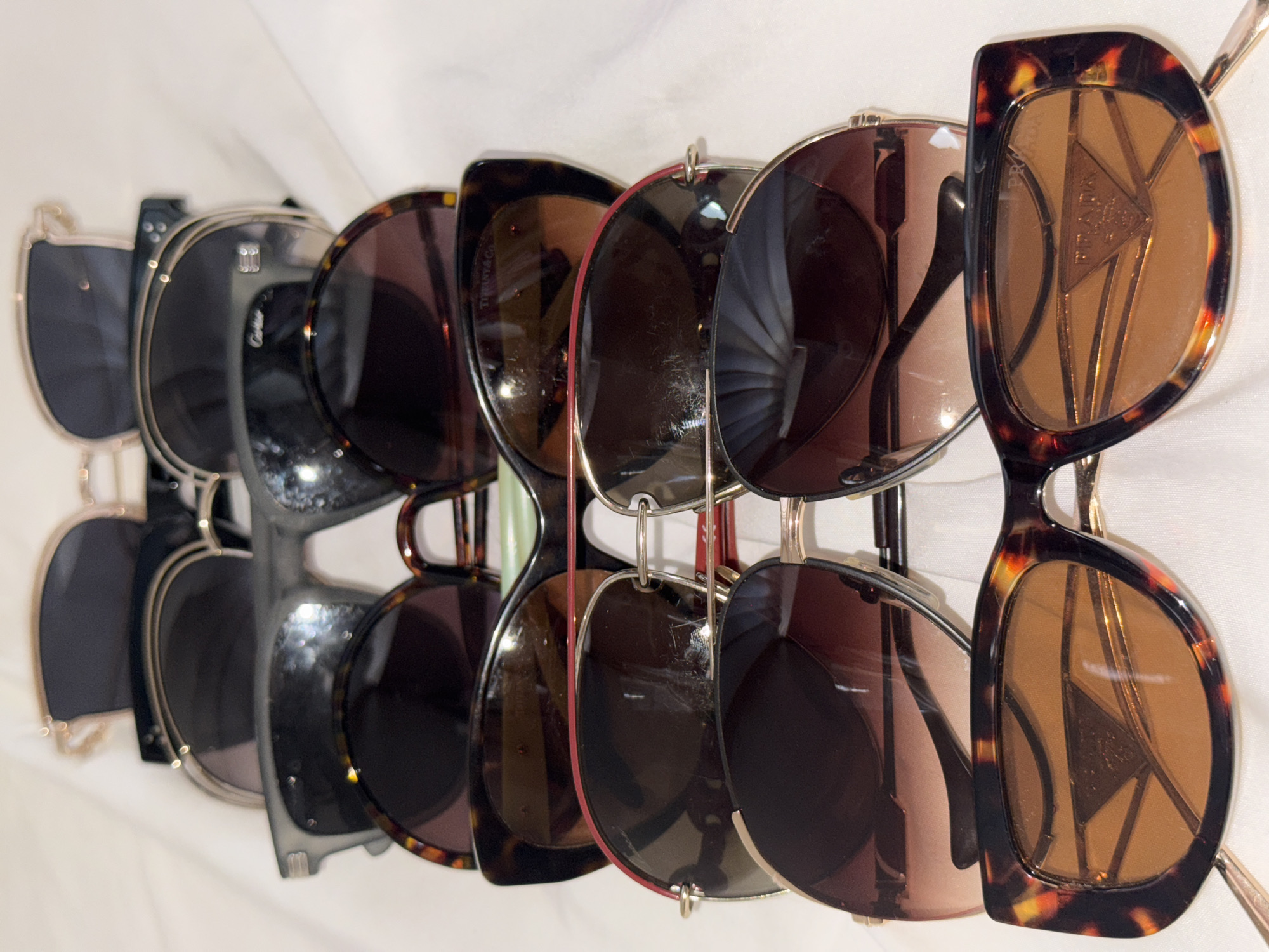 The image displays a rack of sunglasses hanging against a white background. The sunglasses have various frame styles and colors. Brands visible include Prada, Tiffany & Co, and Cartier. The location is not discernible from the image; there is no indication it is in Davao City, Philippines.