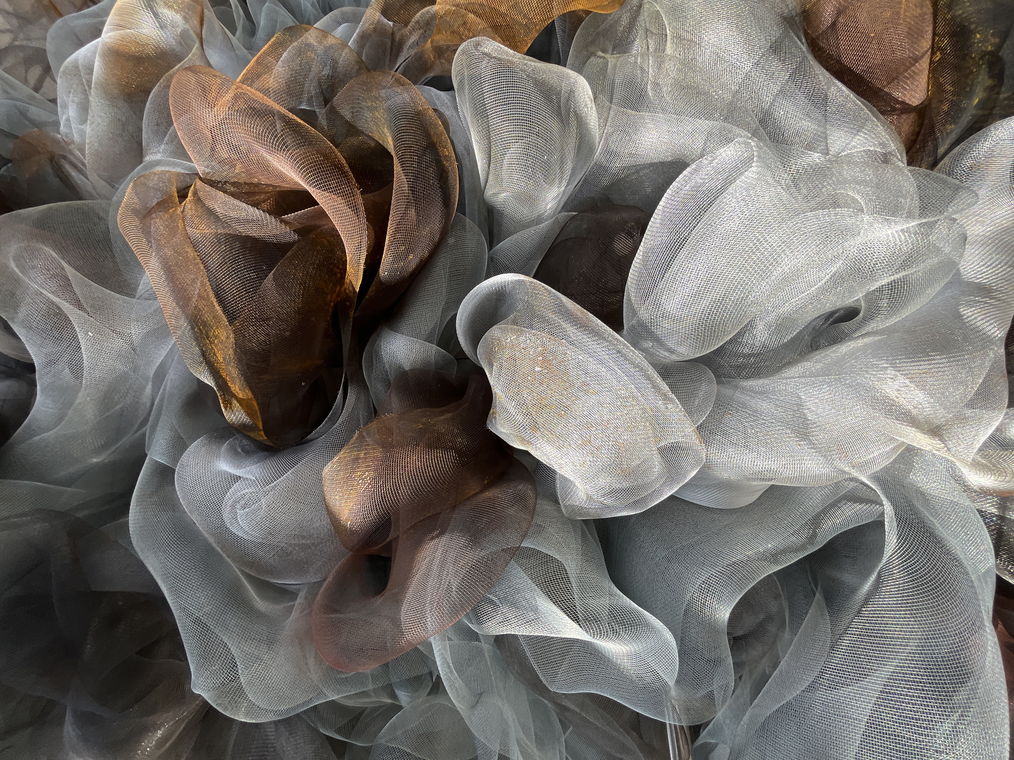 The image shows a close-up view of an arrangement of intertwined, mesh-like materials. The materials are colored in shades of silver-gray and brown. The shapes are organic and rounded, suggesting a deliberate arrangement rather than random disarray. The image does not provide any specific context that would allow for identification of the location in Krasnoyarsk, Russia. There are no people visible in the image.