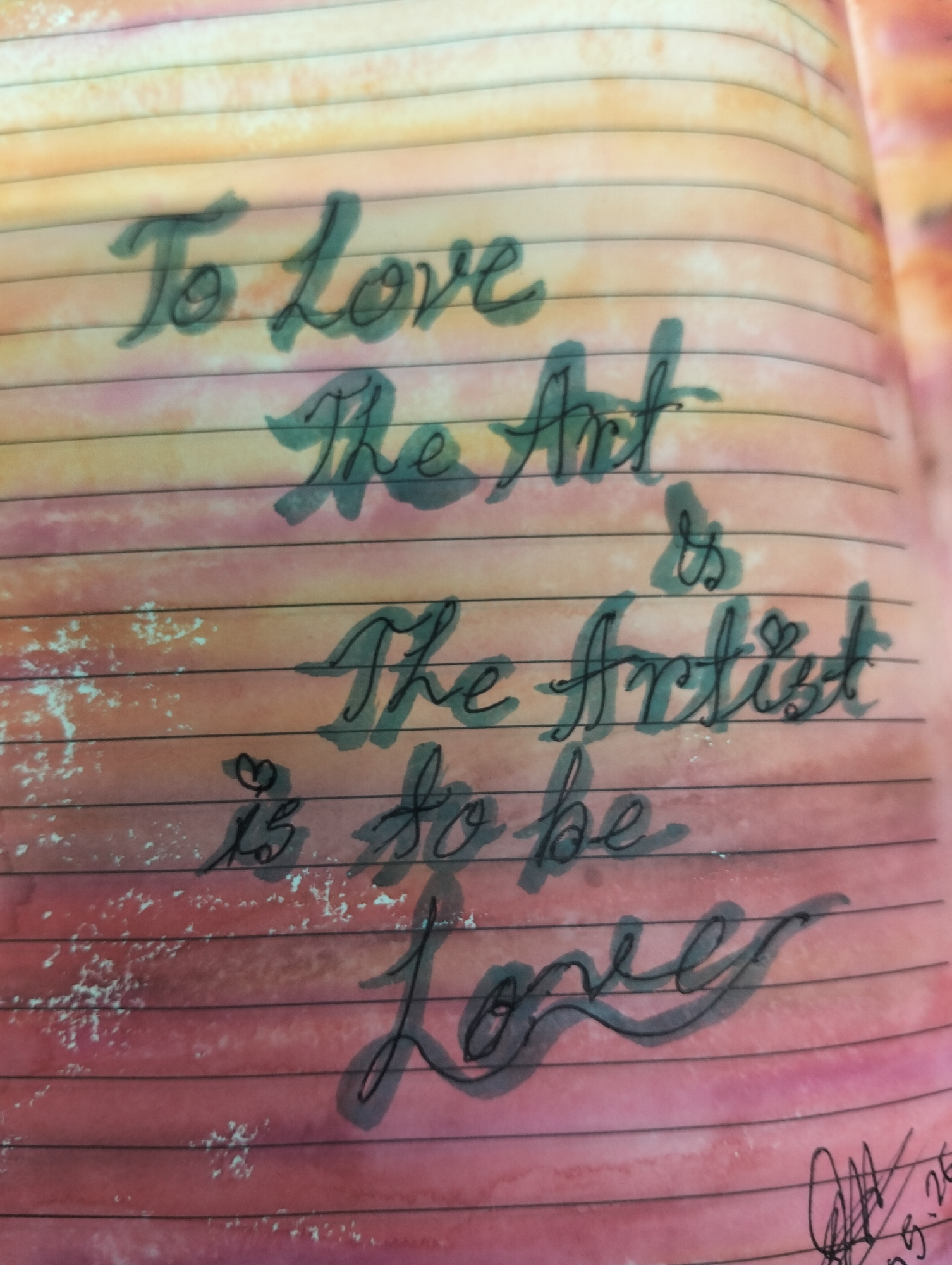 A close-up photograph shows a handwritten quote on lined paper inside a notebook. The text, written in cursive with a dark green pen, reads: "To love the Art is to be The Artist is to be loved". The background of the page features horizontal bands of color, transitioning from peach at the top to shades of pink and red towards the bottom. In the bottom right corner, there is a signature or doodle with some numbers, partially illegible. The paper appears to be textured or stained, and the lines of the notebook are clearly visible. The image captures the personal and intimate nature of handwritten notes. There is no visual information to suggest a location in Dhaka, Bangladesh.