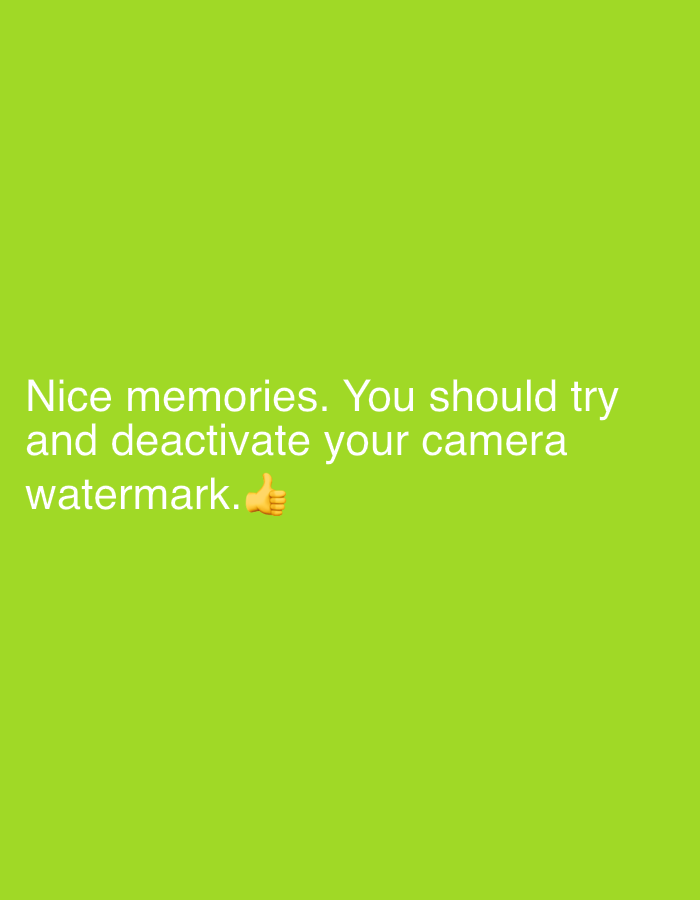 The image is a close-up, eye-level shot of text overlaid on a plain, bright green background. The text is in a light color, appearing white or very pale yellow, and is centrally aligned. It reads: "Nice memories. You should try and deactivate your camera watermark.👍". There are no people, specific objects, or environmental features visible in the image, except for the background and the text itself, which includes a thumbs-up emoji. The location in Ado, Nigeria is not visually depicted or inferable from the image content.