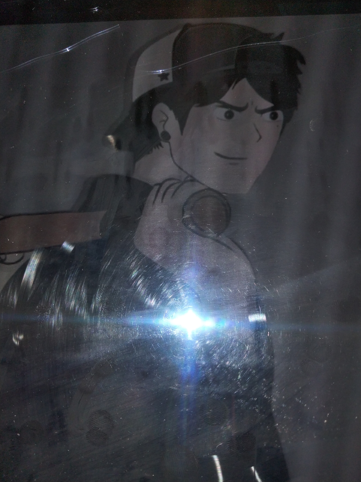 The image is a close-up, dimly lit, and appears to be a photograph of an anime-style drawing, possibly on a surface with a protective plastic covering, as evidenced by glare and scratches. The drawing depicts a young male with dark hair, wearing a baseball cap. He has an intense expression with furrowed brows and wide eyes, looking off to the side. He is wearing headphones around his neck and holding what appears to be a baseball bat over his shoulder. The lower half of the drawing is obscured by bright glare and reflections from the lighting source. There is no discernible information within the image to suggest a location in Payagaboh, Indonesia, or any urban environment. The scene is static and focused on the artistic representation of a single character.