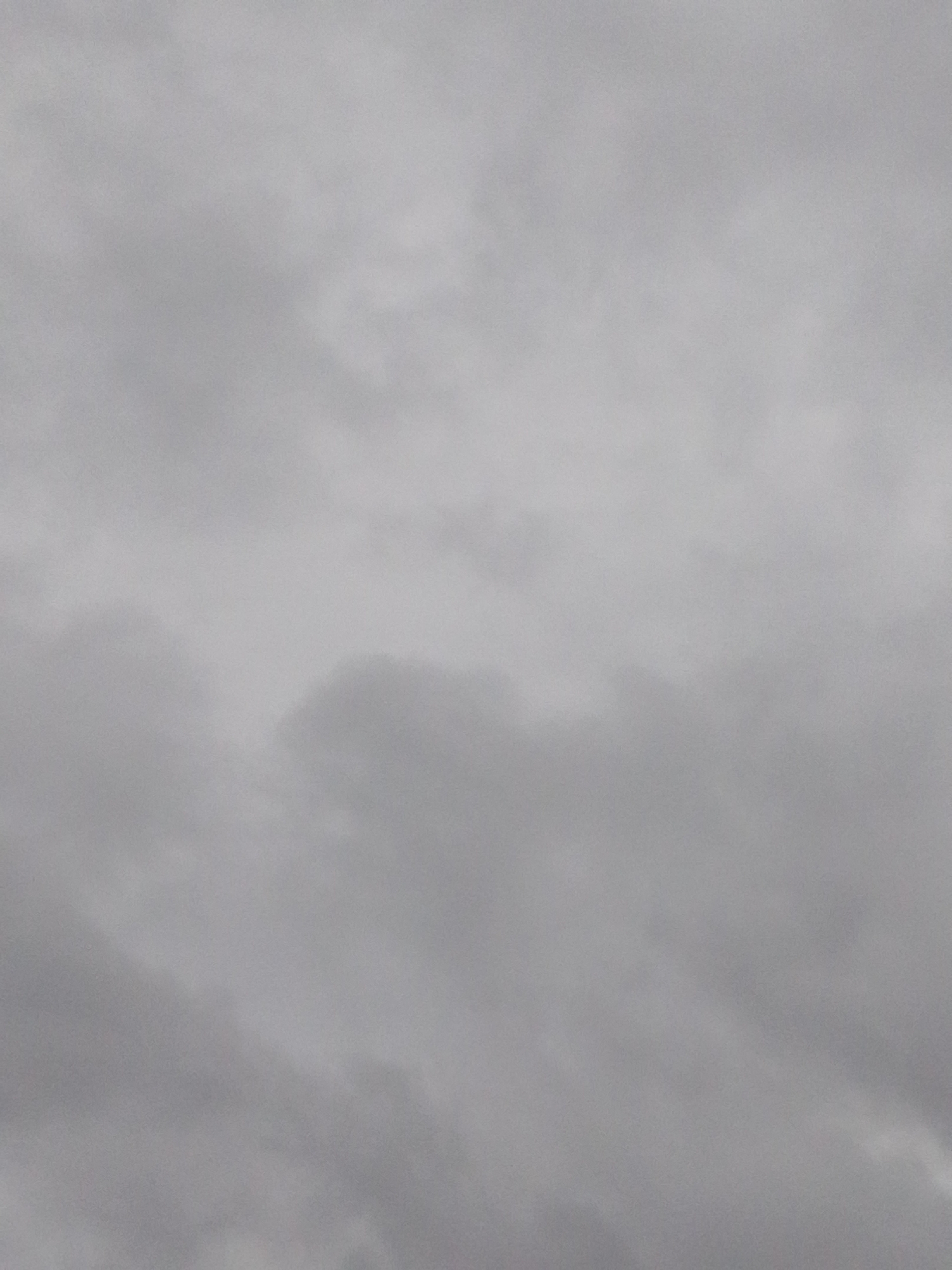 This is a photograph of a cloudy sky with no visible landmarks, structures, or people. The image is predominantly gray, suggesting overcast weather. The texture of the clouds is soft and diffused, with varying shades of gray indicating depth and shadow. There are no discernible objects or activity within the frame. The location in Serti, Nigeria, is not visually represented in this image.