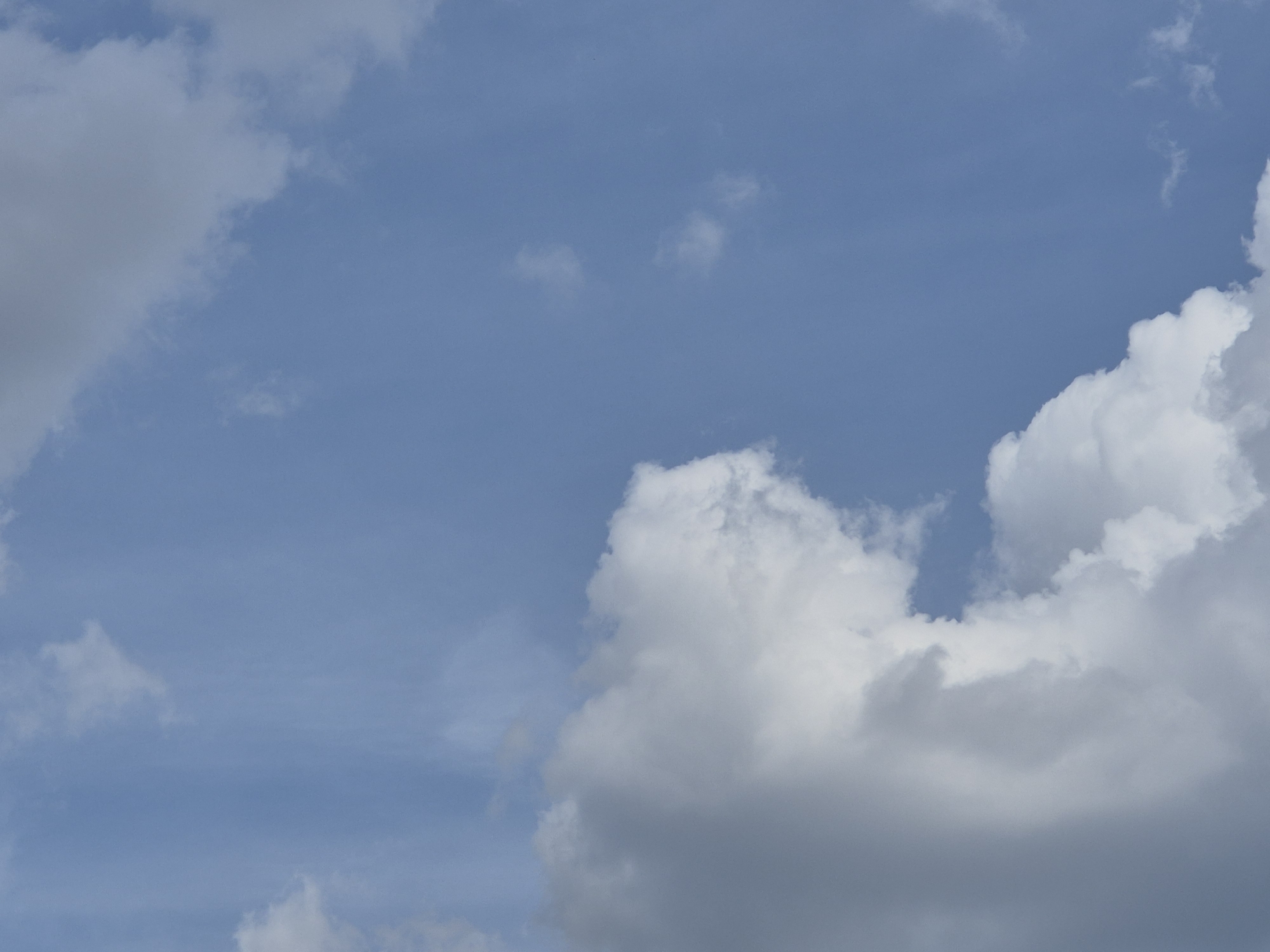 The image depicts a cloudy sky with varying cloud formations. The sky is a clear blue, with white and gray clouds scattered across it. Some clouds are wispy and thin, while others are large and fluffy. The clouds in the foreground are darker and more dense, suggesting they are closer to the viewer. The image does not contain any information that would allow for the identification of a specific location in Sofia, Bulgaria, or any people, subjects, or actions.