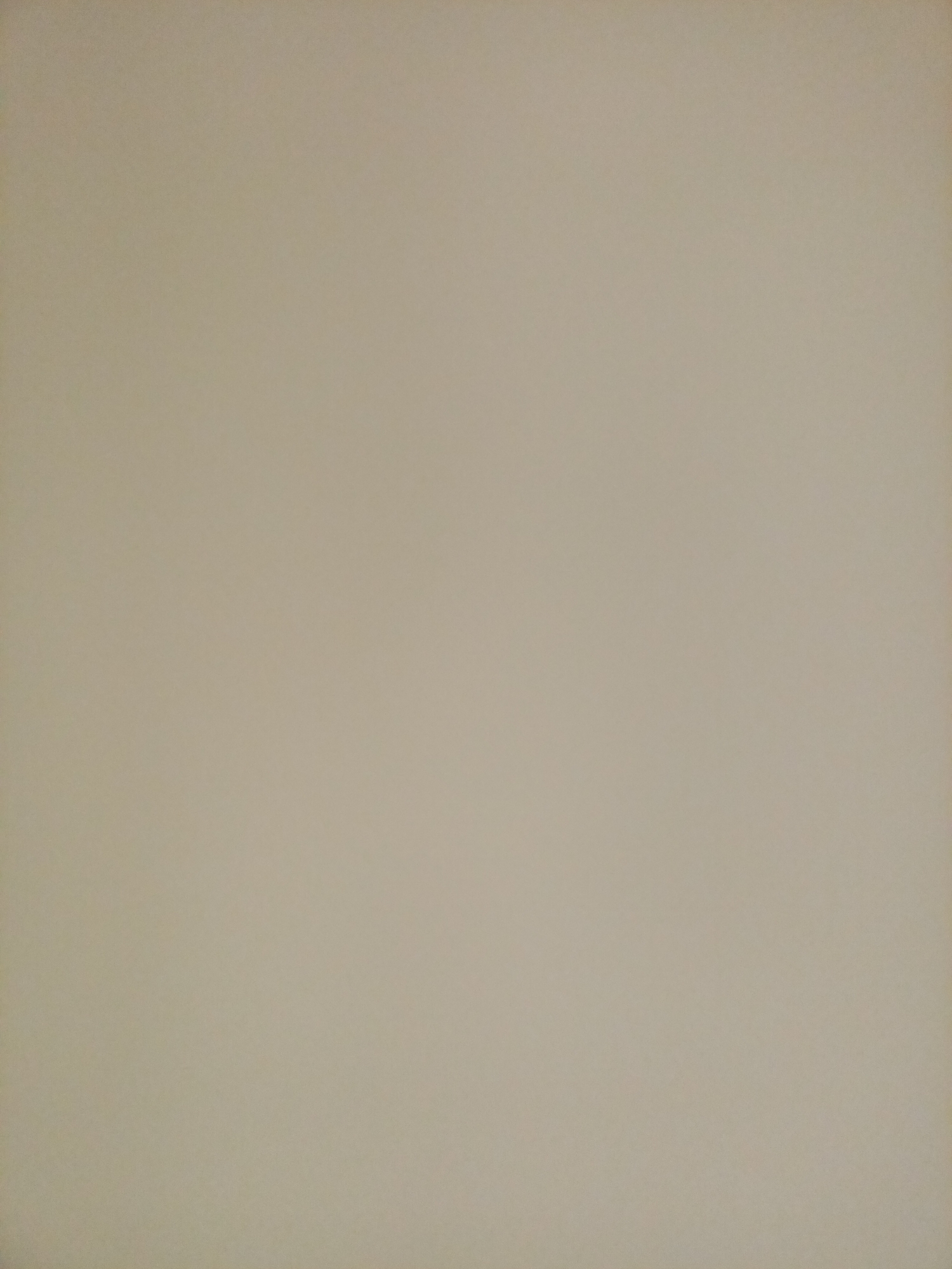 The image shows a uniform, light brown textured background. There are no discernible objects, people, or actions within the frame. The texture appears to be consistent throughout, suggesting a wall or a similar flat surface. The lighting is even, with no shadows. The image is a static, featureless depiction of a neutral surface.