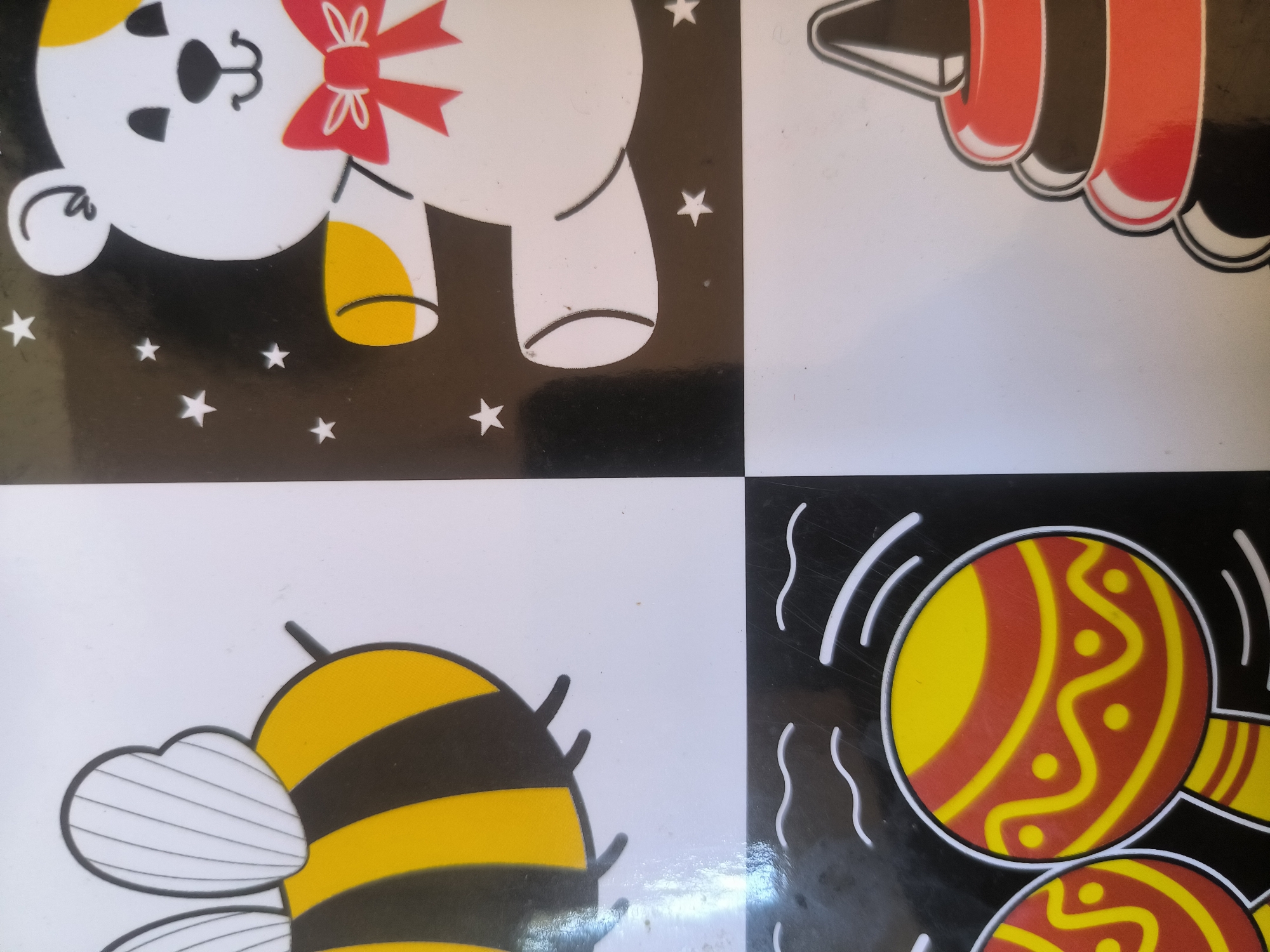 The image shows a set of four black-and-white contrast cards arranged in a square formation.
* **Top Left:** A stylized bear illustration with a red bow tie, stars are visible on the black background.
* **Top Right:** A simple image of a crayon.
* **Bottom Left:** A cartoon bee design with stripes and translucent wings.
* **Bottom Right:** A depiction of maracas with yellow and red patterns.
The image does not provide information about the city of Lhokseumawe, Indonesia.