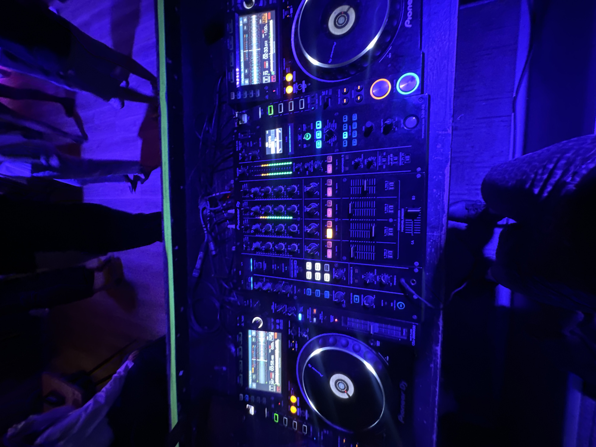 The image shows a Pioneer DJ setup, consisting of two CDJ-2000NXS2 players and a DJM-A9 mixer, mounted vertically in a dark environment. The lighting is predominantly blue. The surrounding environment includes abstract shapes and figures, likely decorations or architectural elements within the venue. The location is Moscow, Russia.